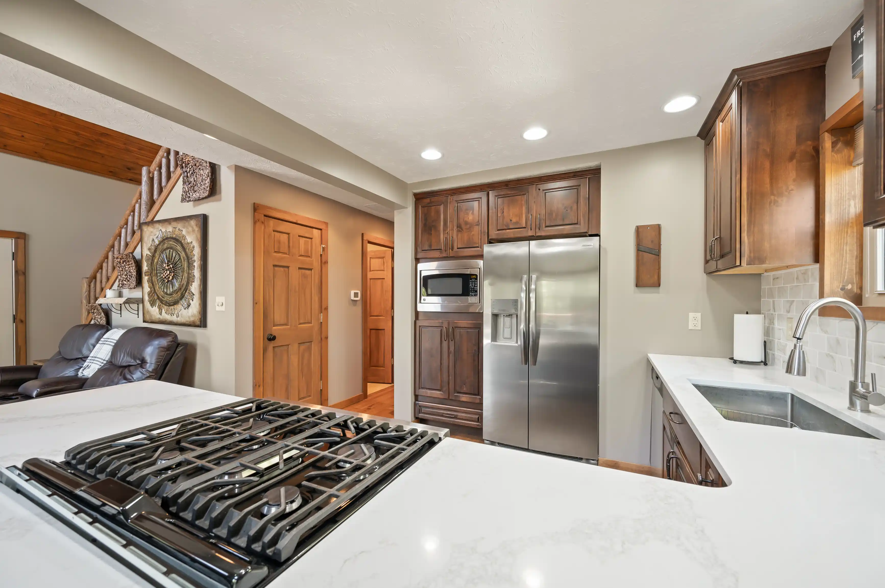 Modern kitchen interior with stainless steel appliances, wooden cabinets, and a white marble countertop.