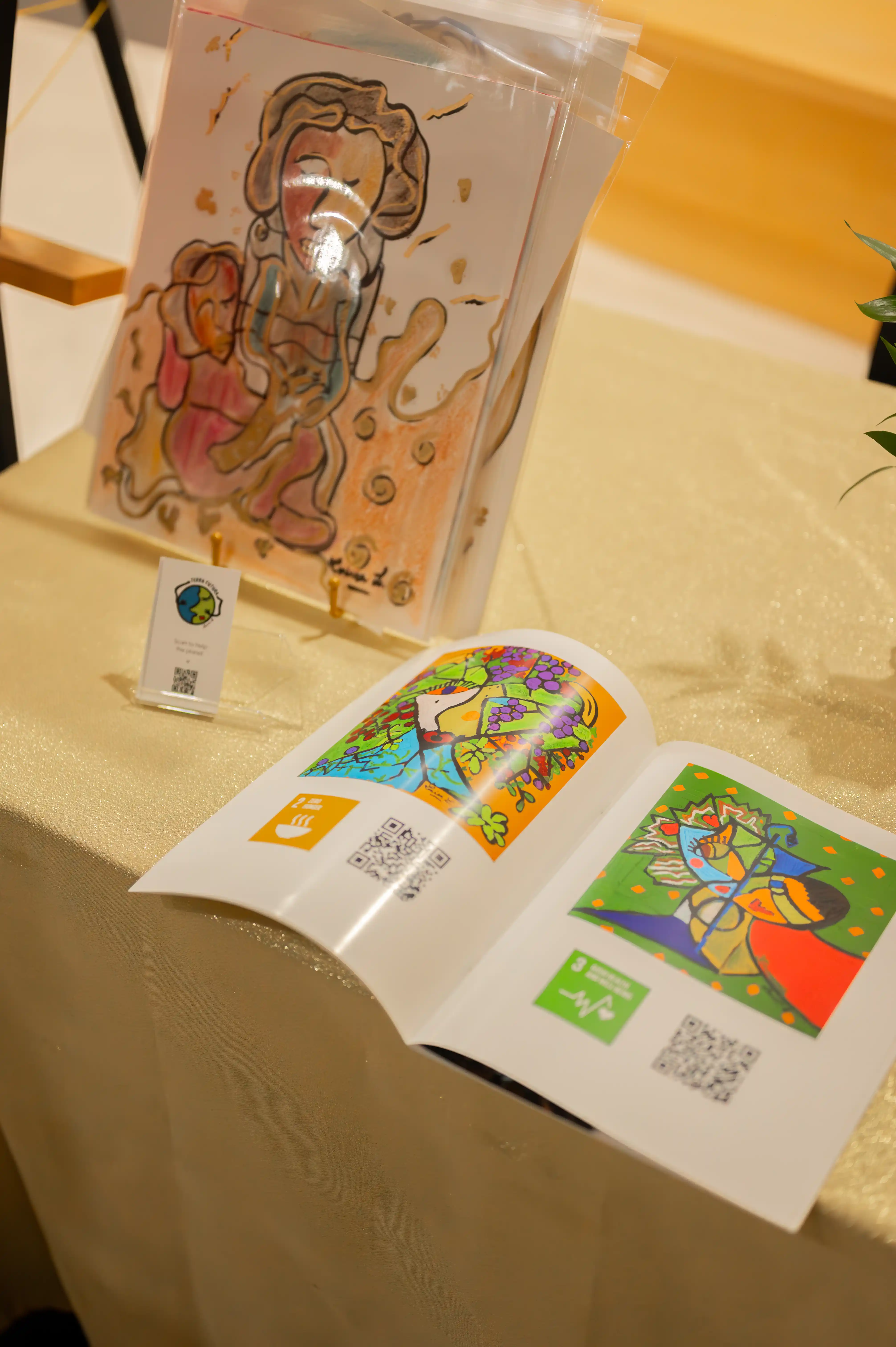 Alt: Coloring book opened to a page with vibrant, colored artwork on a table next to colored pencils, with another coloring book standing upright in the background.