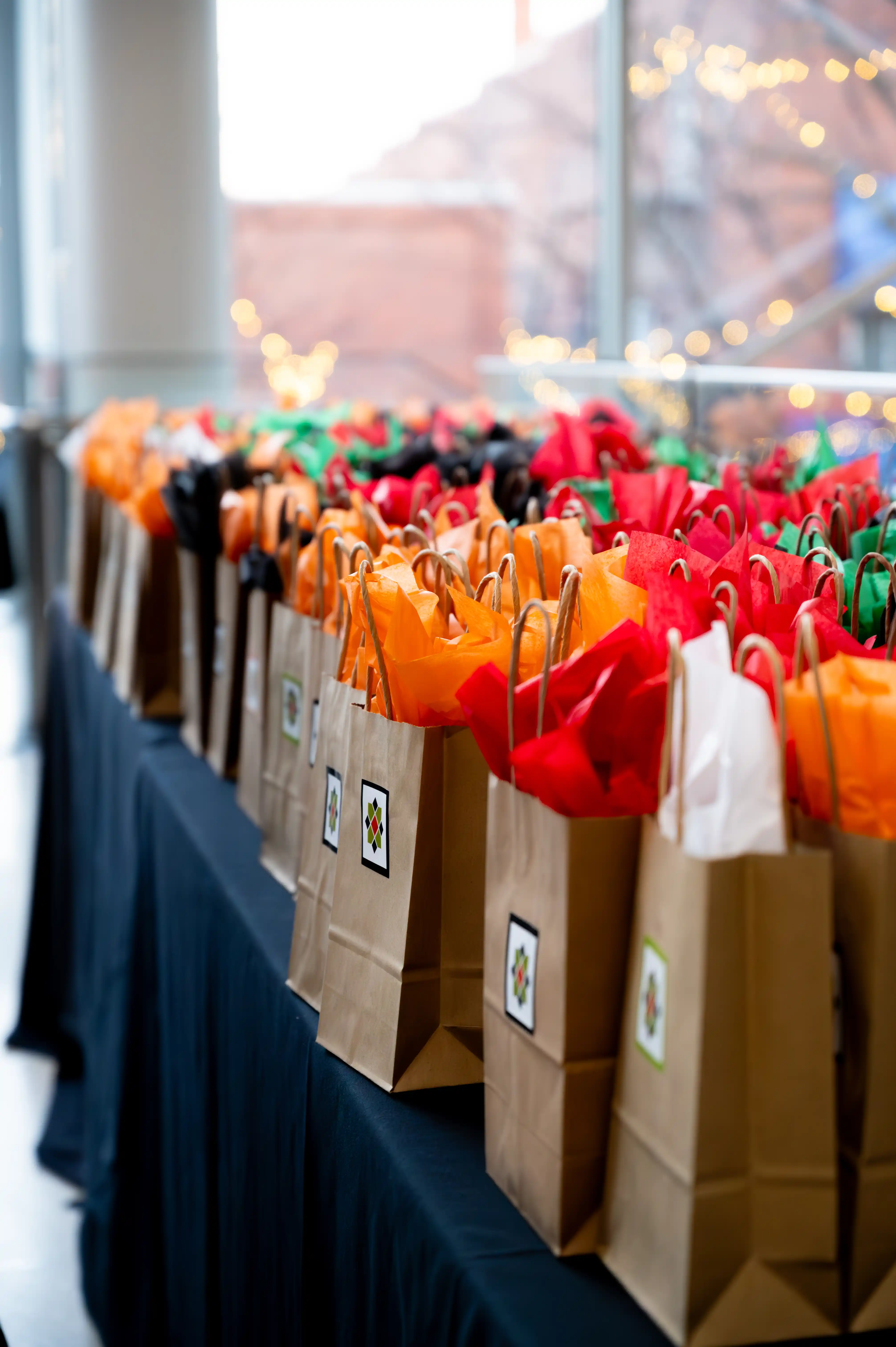 Row of paper goody bags with colorful tissue paper lined up on a counter.