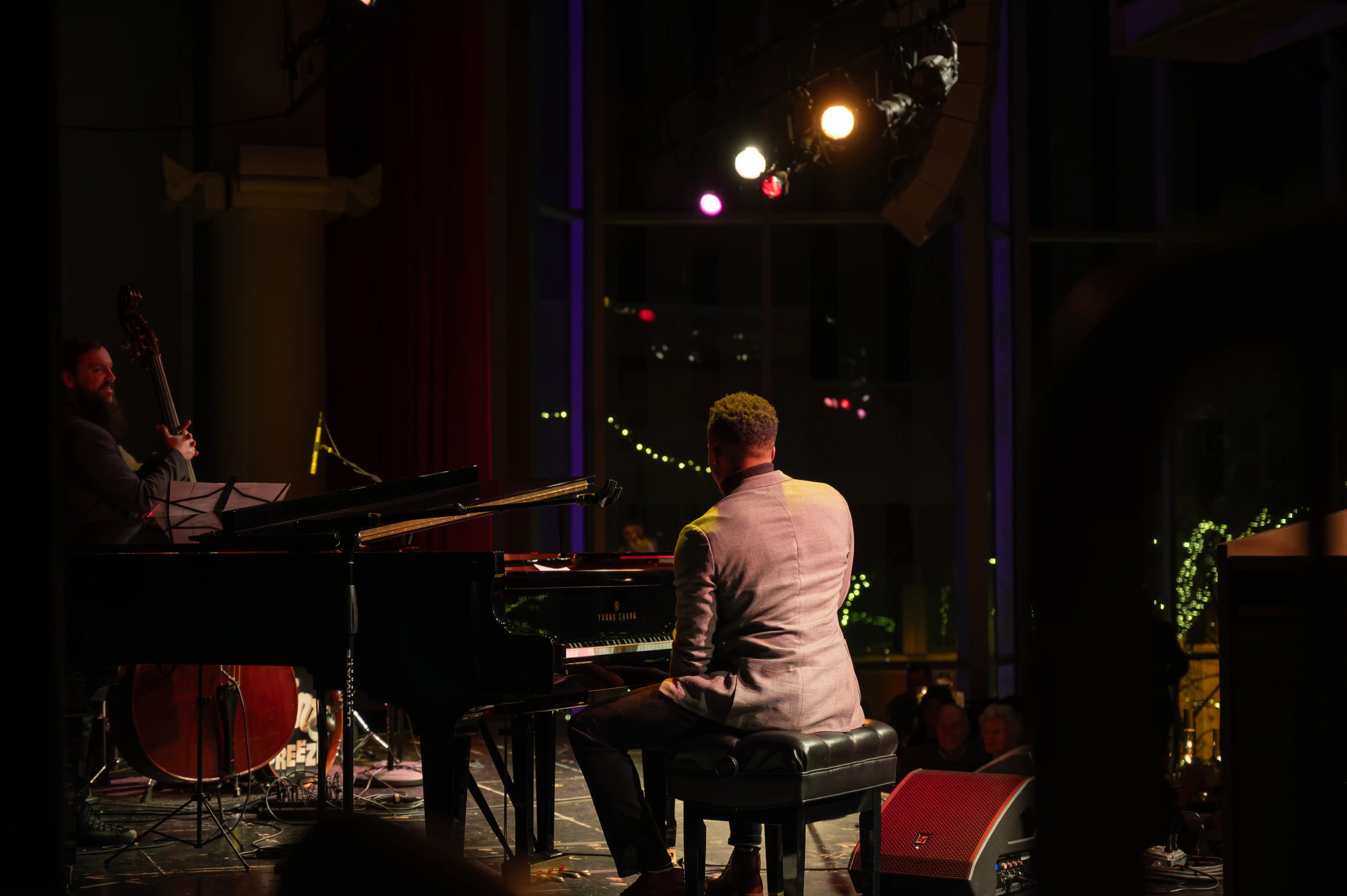 Pianist and musicians performing on stage under dim stage lighting.