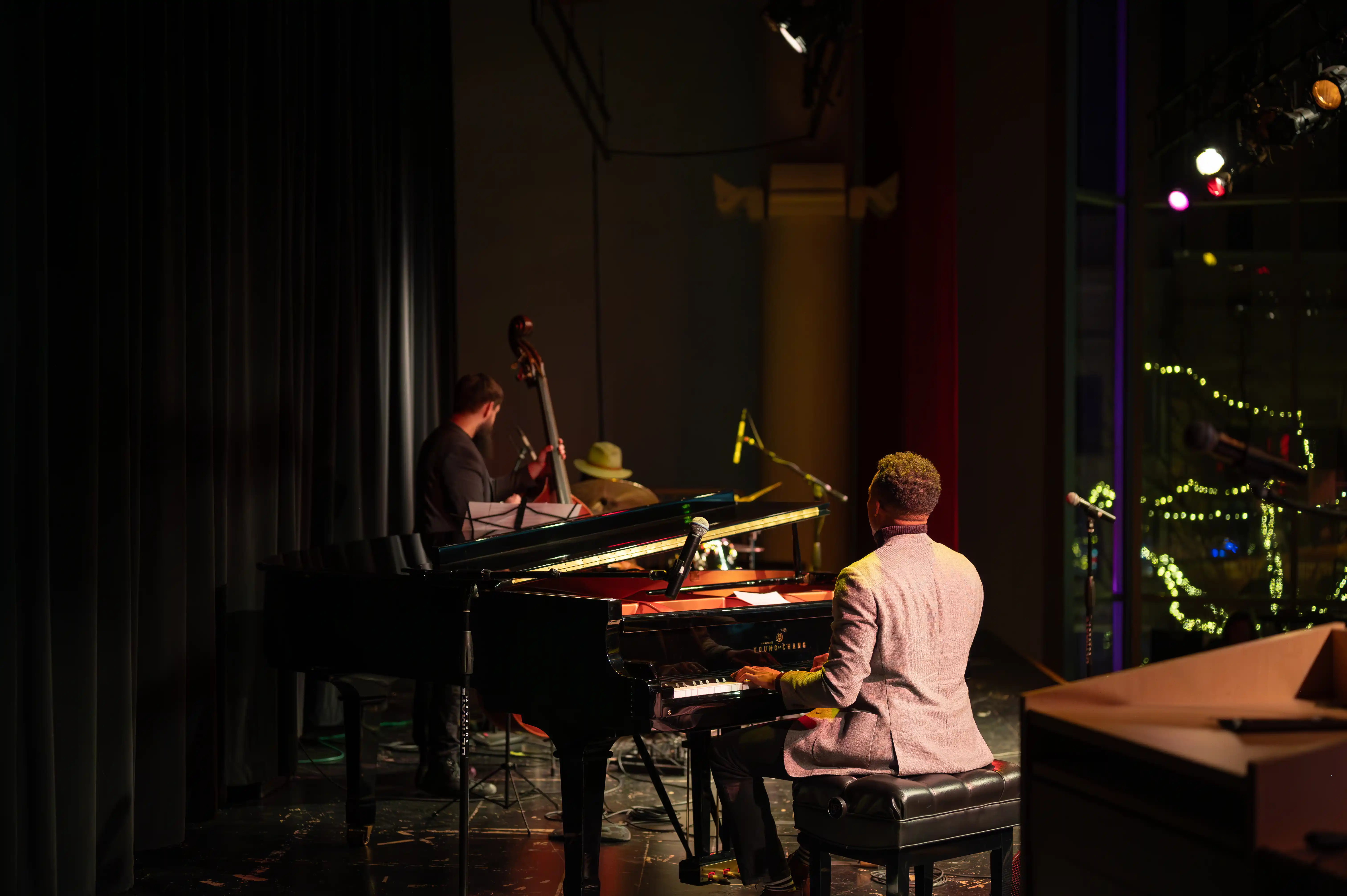 Musicians on stage with a pianist in focus and a double bass player in the background during a live performance.