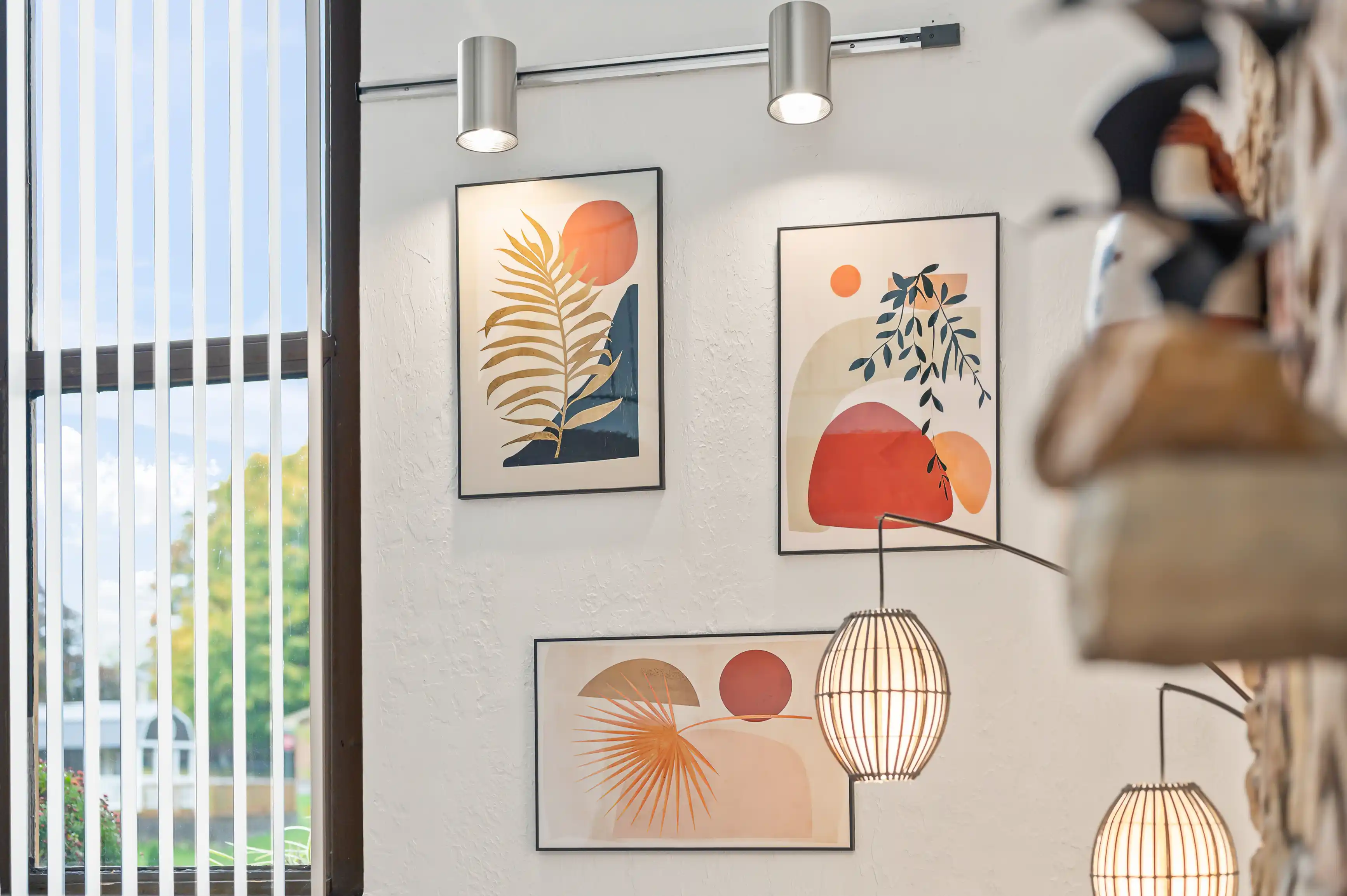 Modern artwork on a gallery wall with stylish hanging lamps in an interior setting.