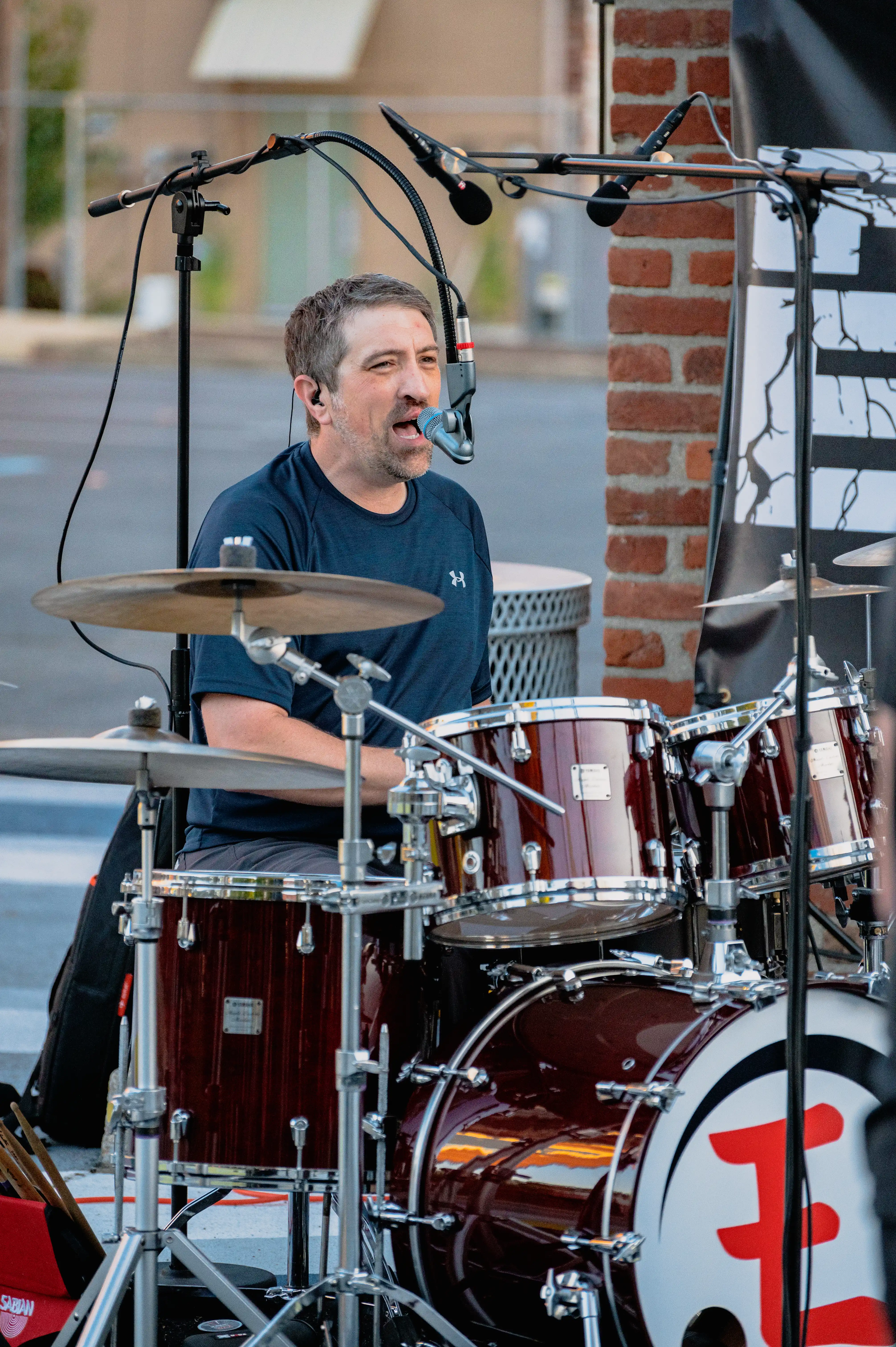 Drummer performing on stage with a red and white drum set.