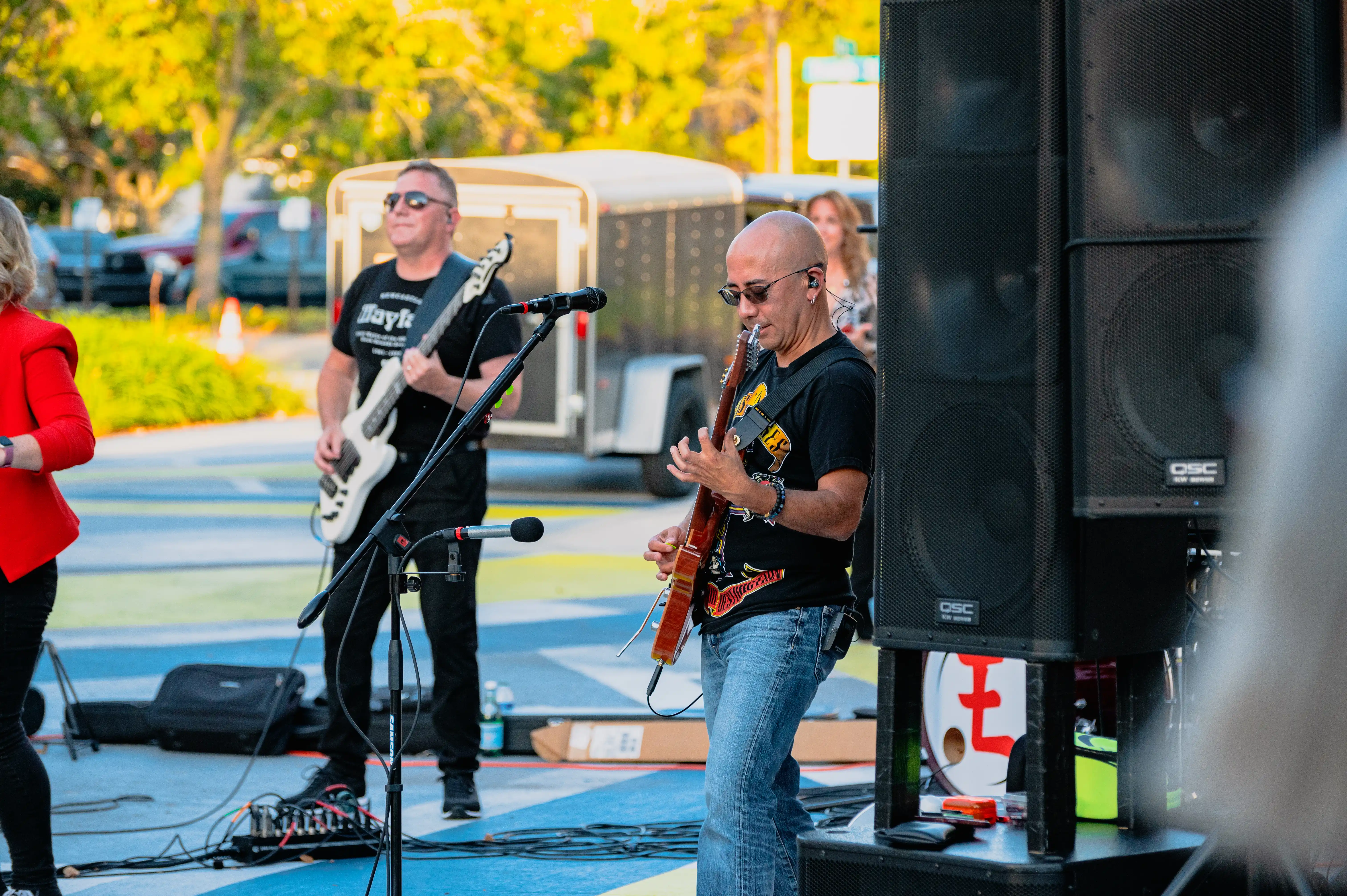 Band members performing at an outdoor event, with focus on a guitarist playing an electric guitar.