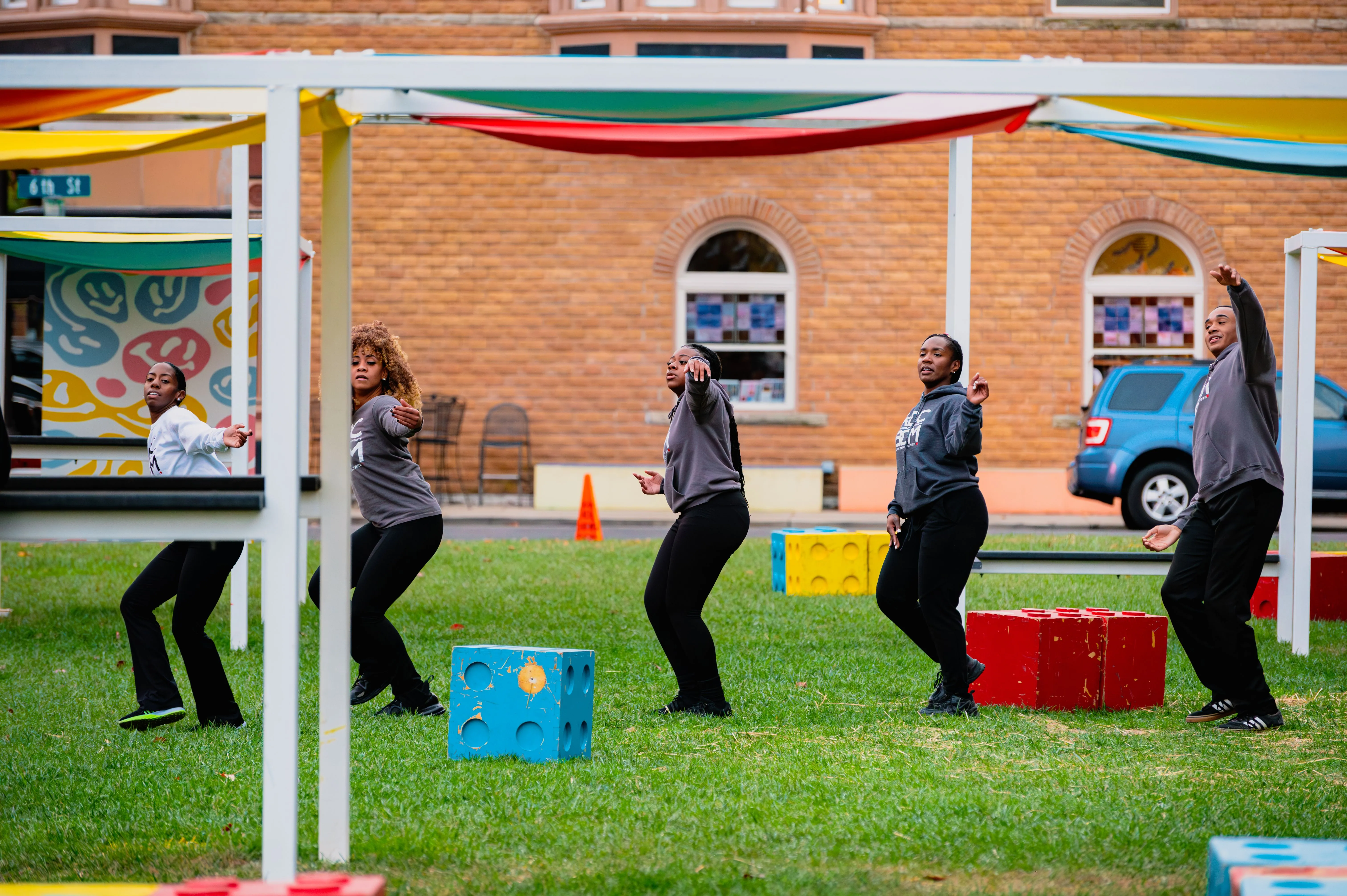 People engaging in an outdoor team building activity with colorful ribbons overhead.