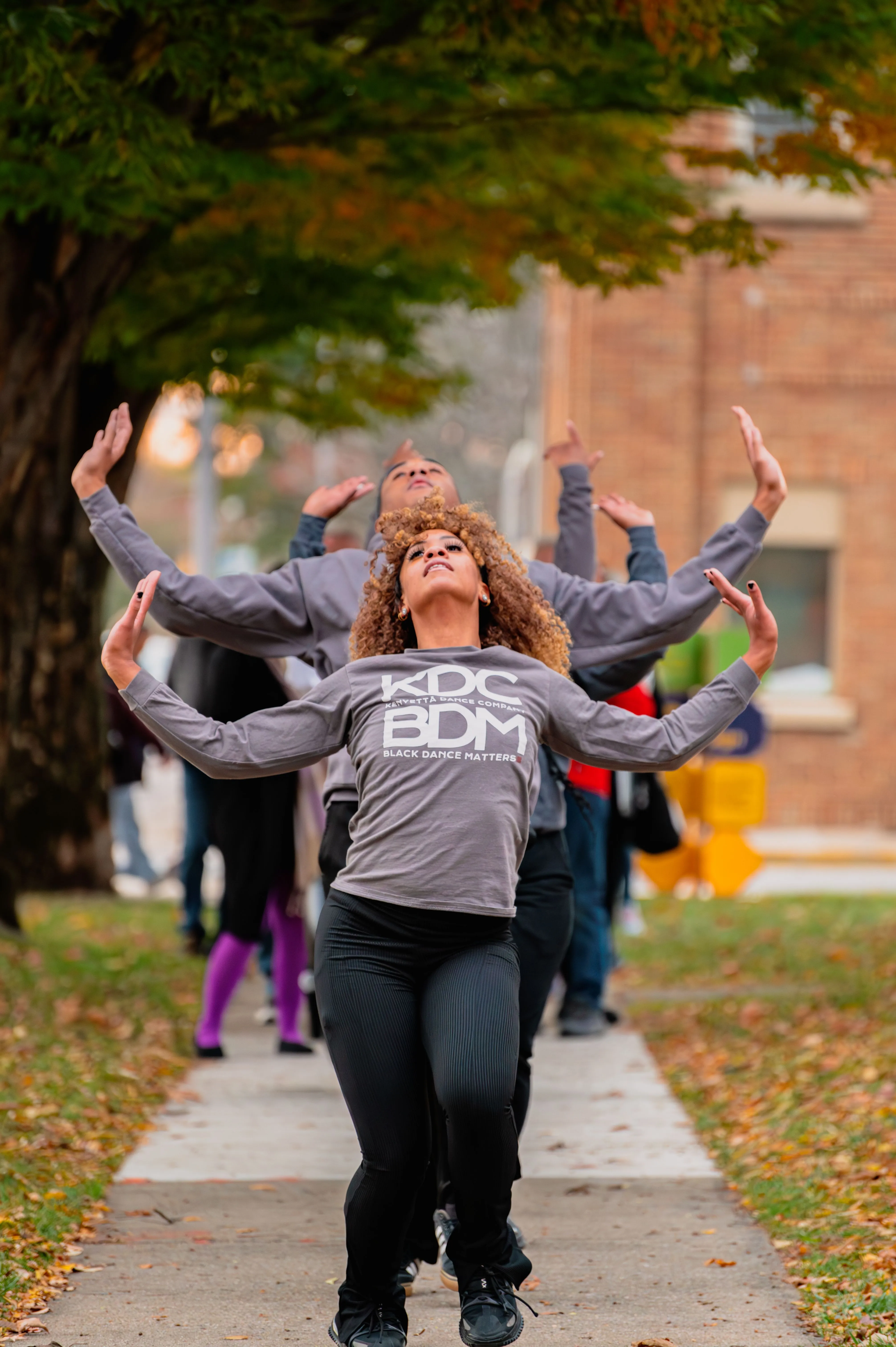 Group of joyful students walking on a campus pathway in autumn.