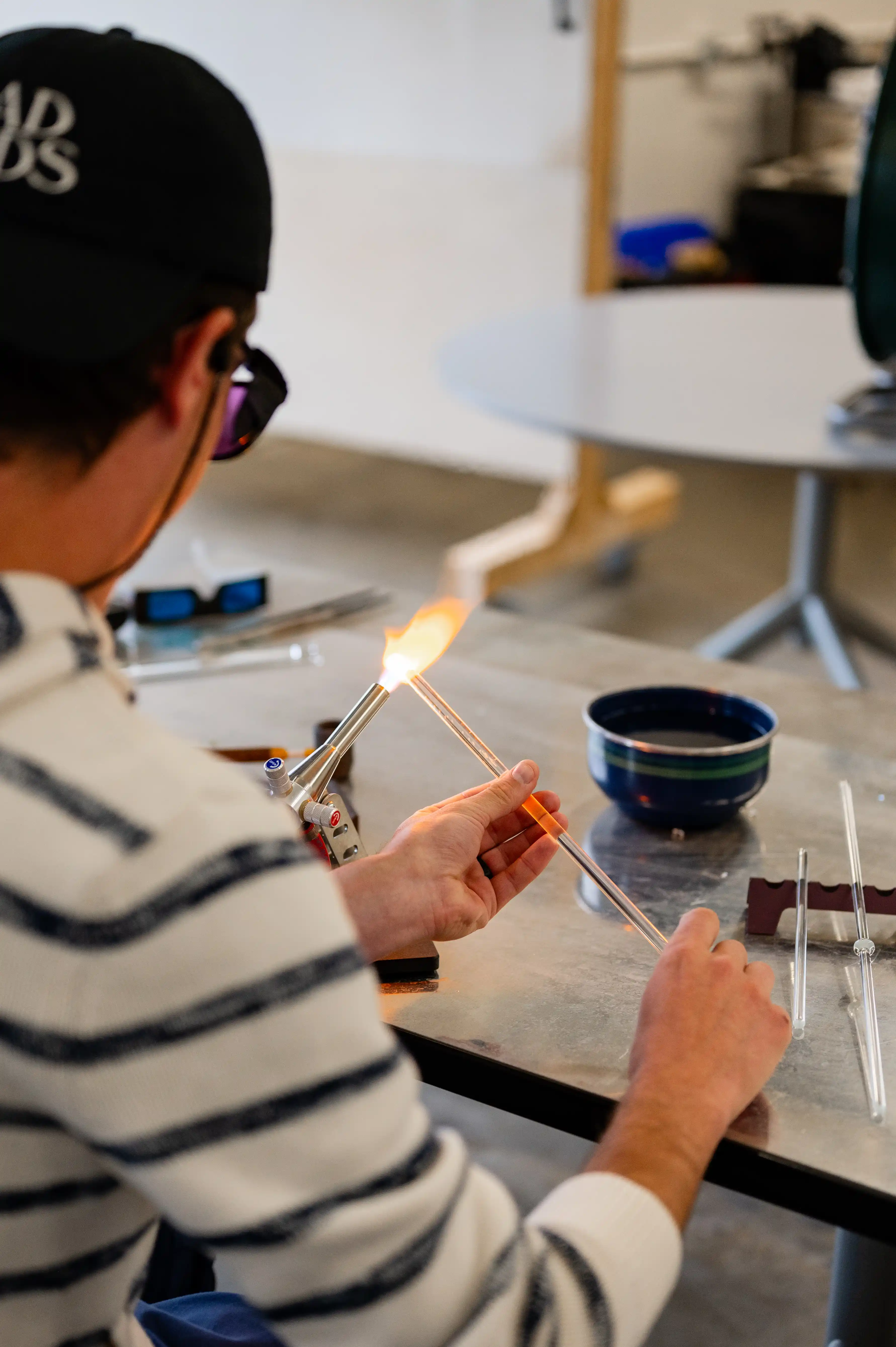 Person using a glassblowing torch to shape a piece of glass.