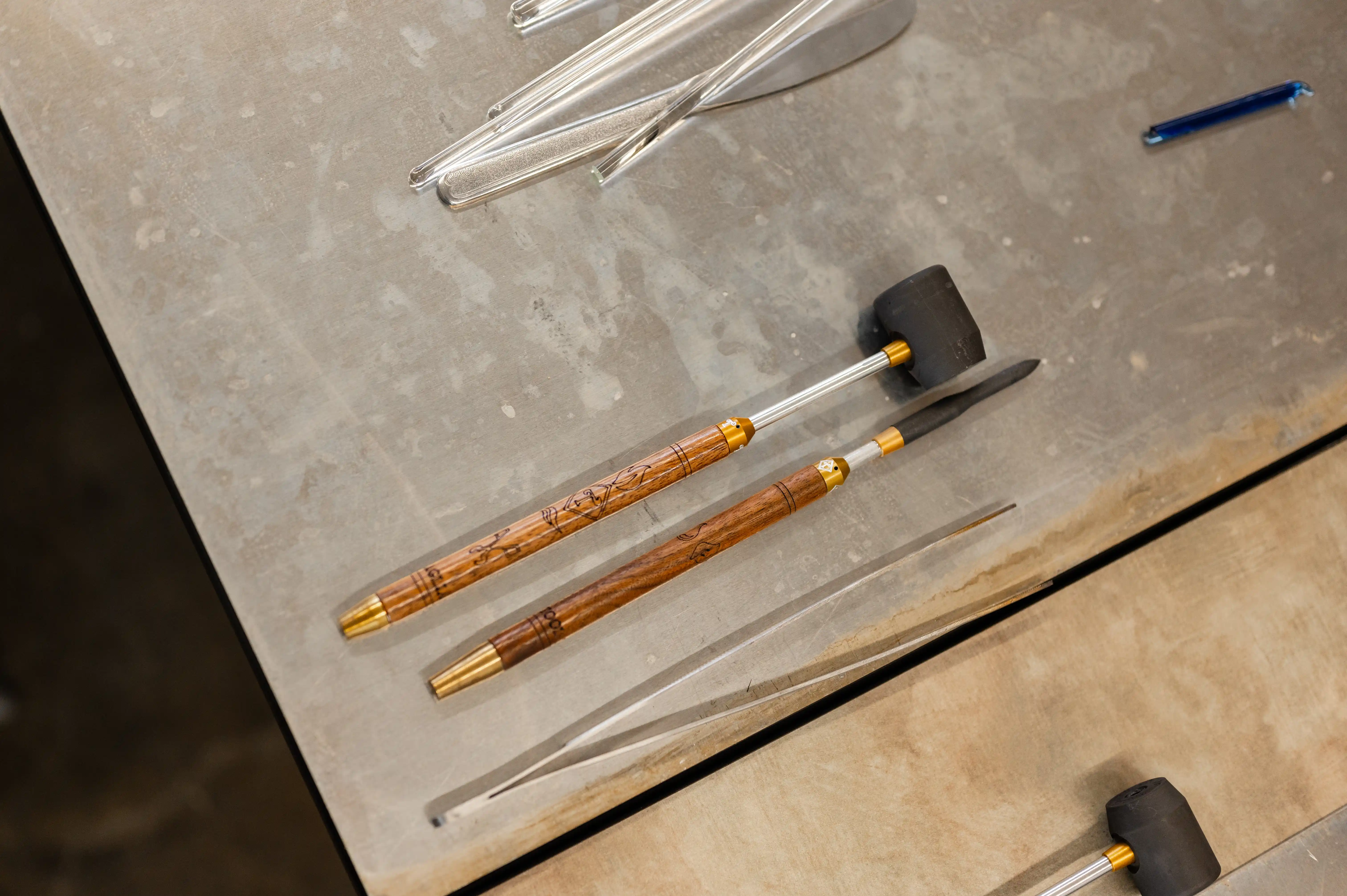 Craftsman workbench with an assortment of tools including chisels with wooden handles, a rubber mallet, and a blue plastic pen.