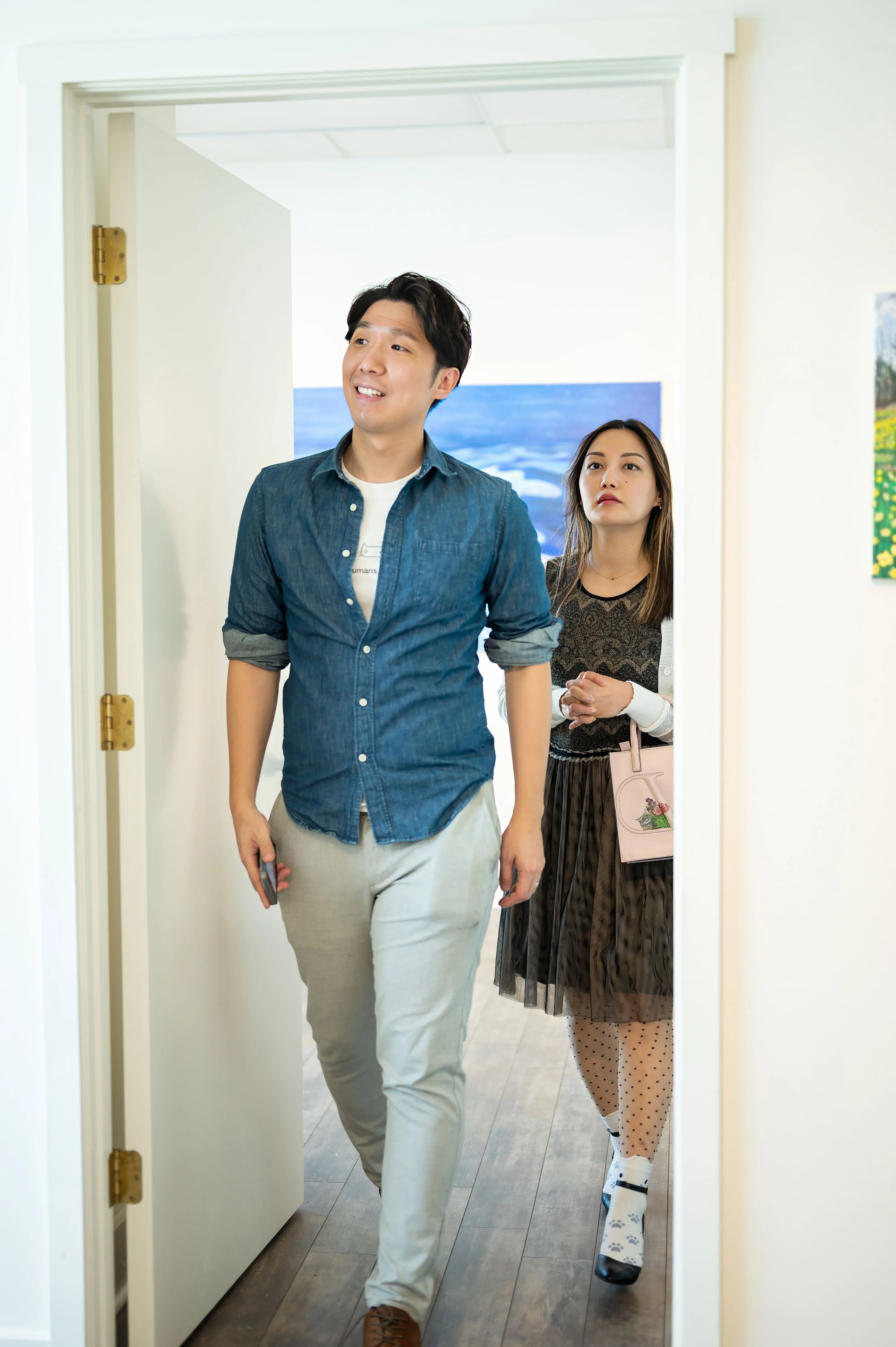 Man and woman walking through a doorway into a bright room.