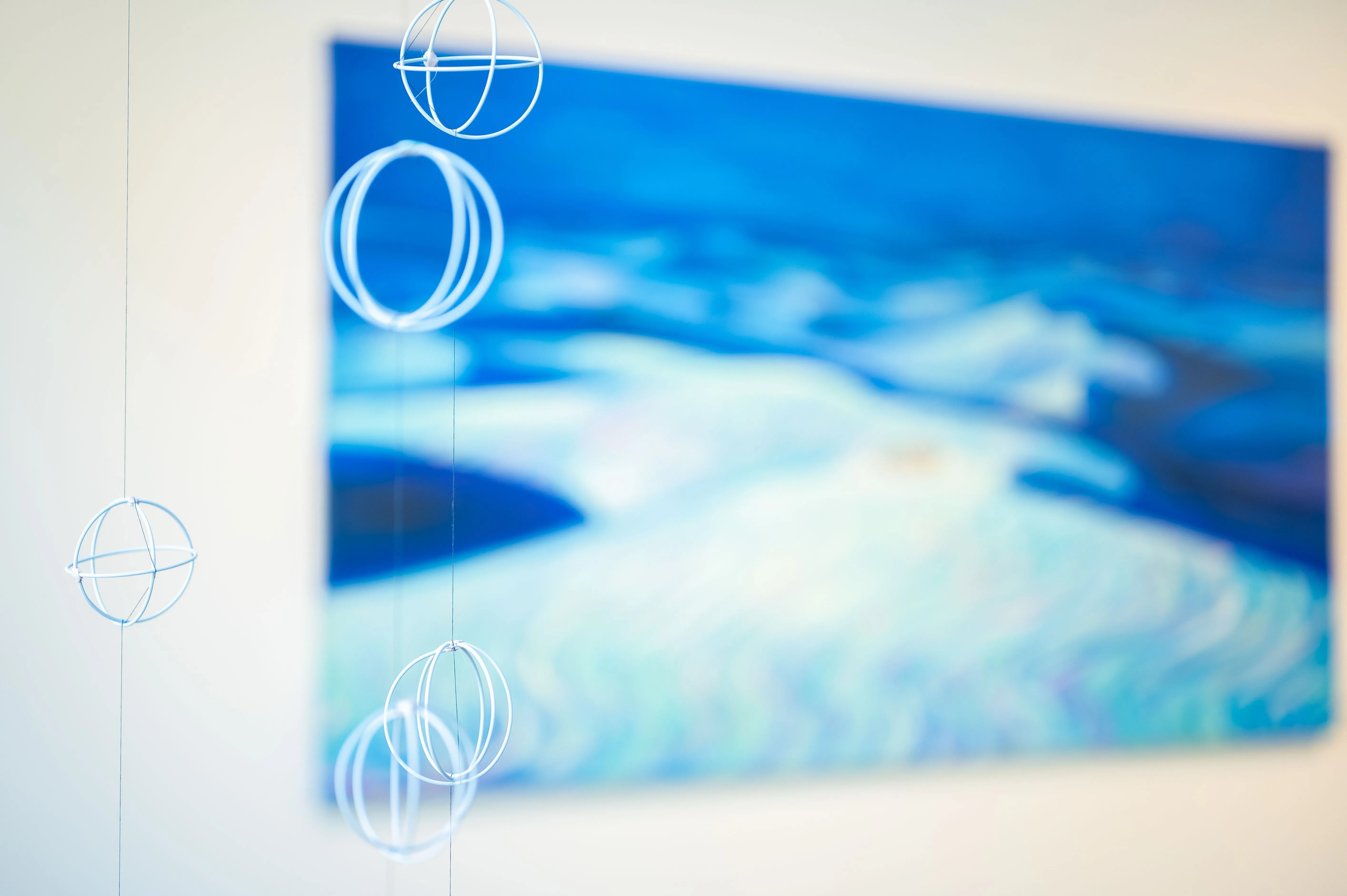 Blurred image of a canvas with abstract blue and white art on a wall, overlayed with transparent circles possibly representing artistic inspiration or creativity.