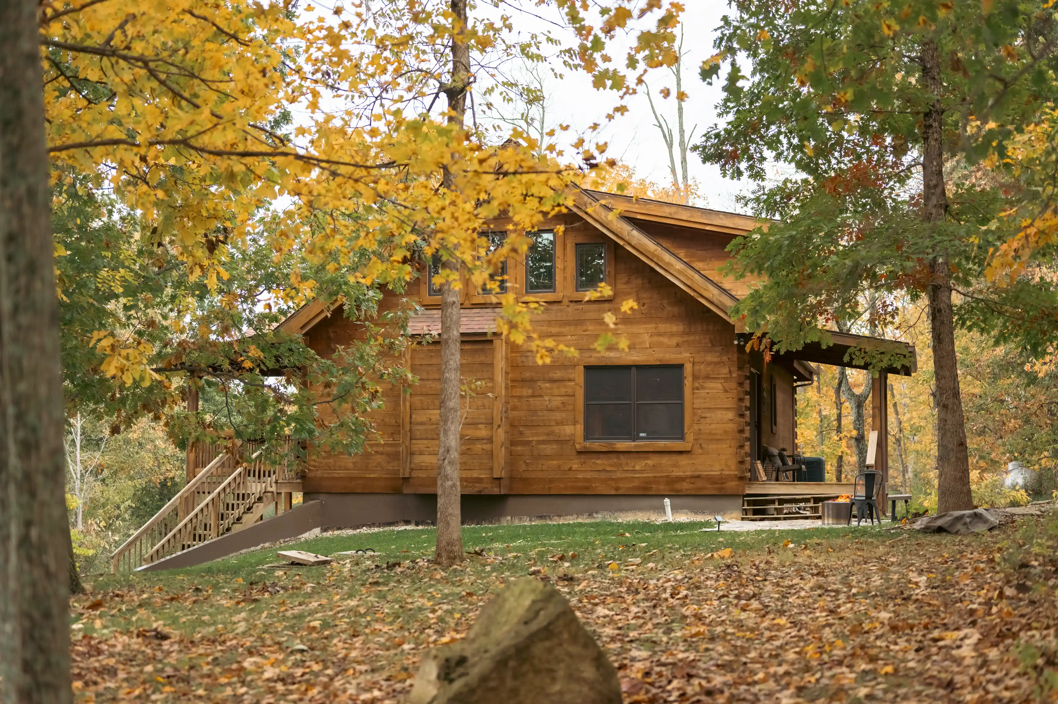 Wooden cabin surrounded by autumn foliage with a front porch and staircase.