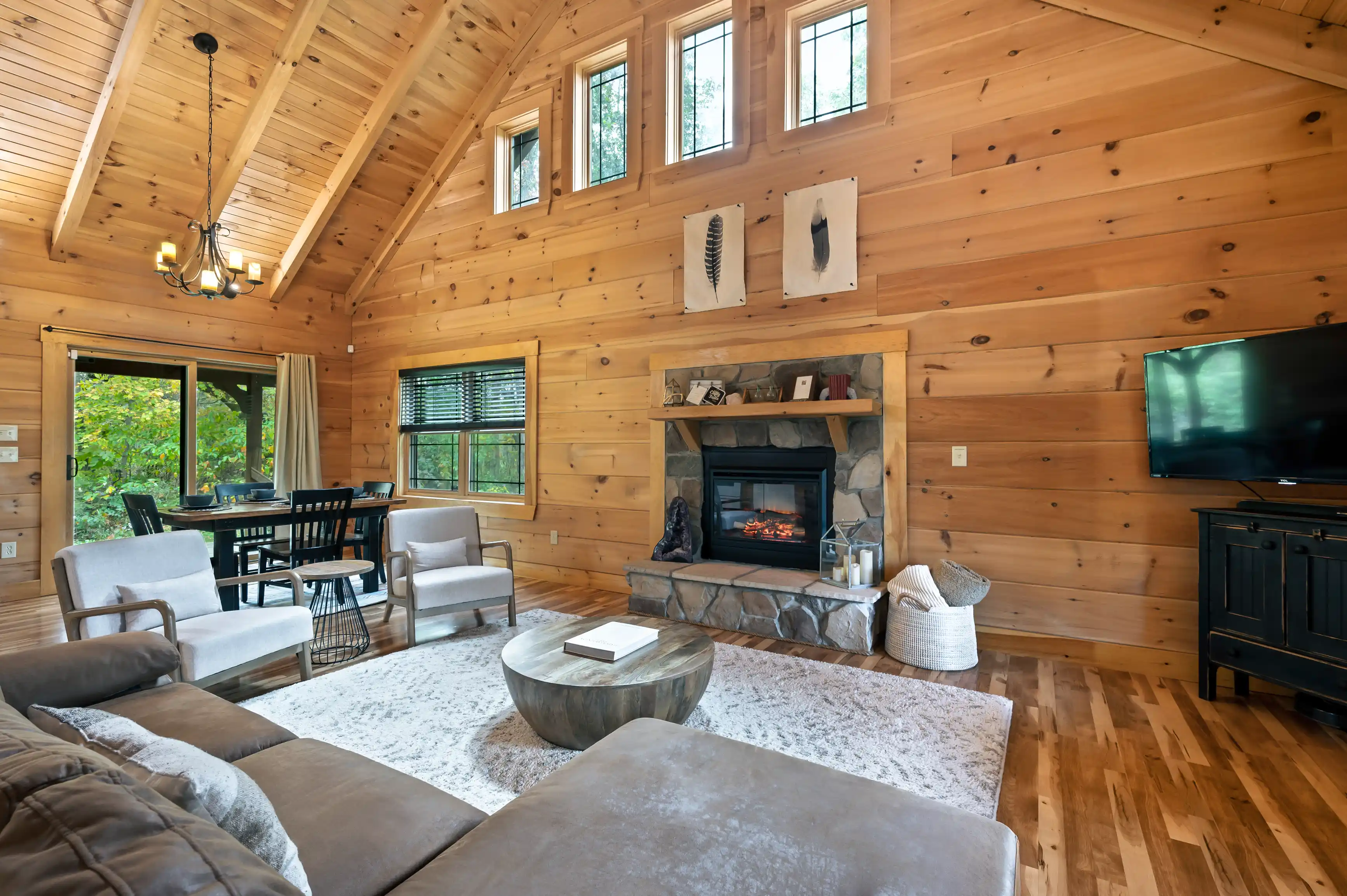 Cozy living room interior in a wooden cabin with a fireplace, comfortable seating, and modern amenities.