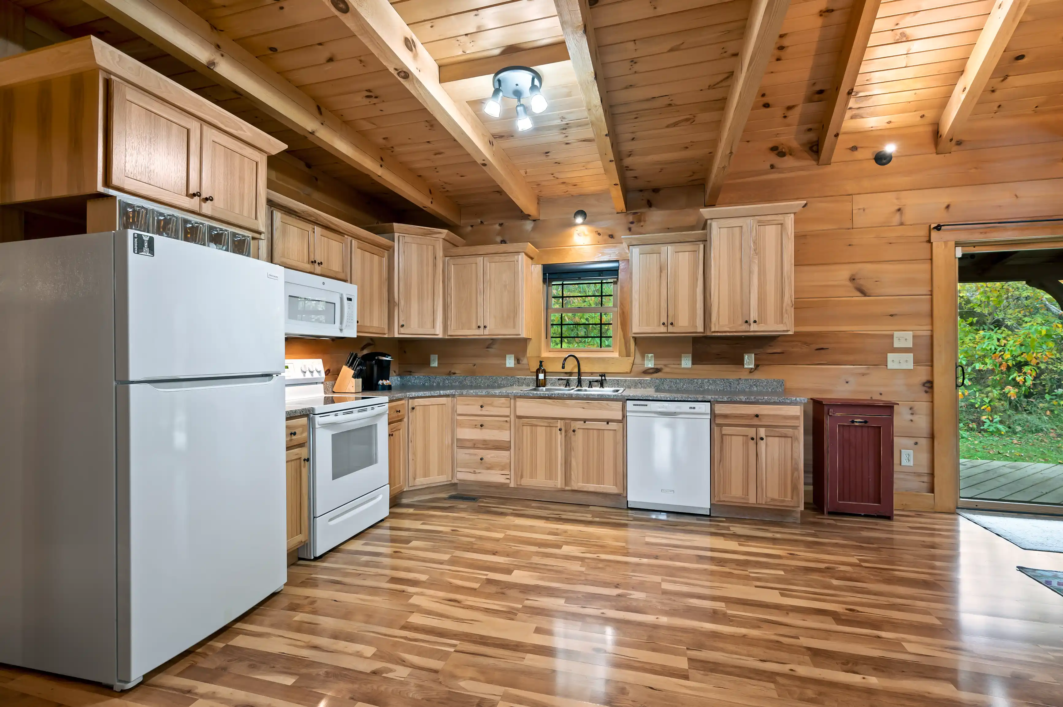 Interior of a modern kitchen with wooden cabinets, stainless steel appliances, and hardwood floors.