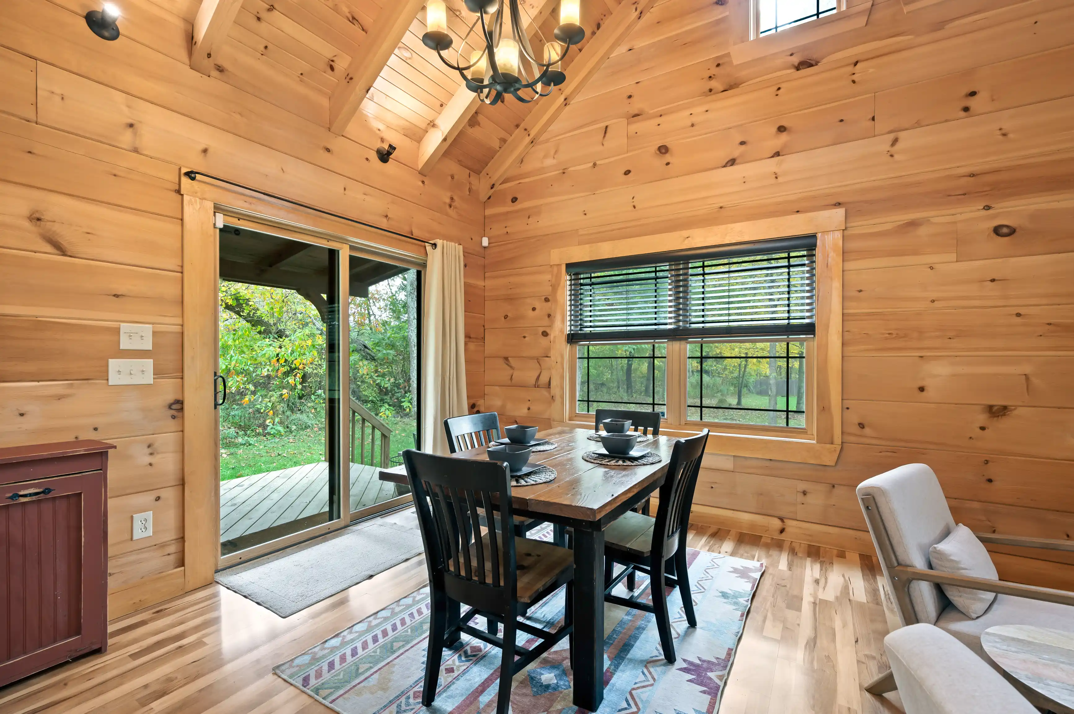 Cozy wooden cabin interior with a dining table set, open patio door, and natural light.