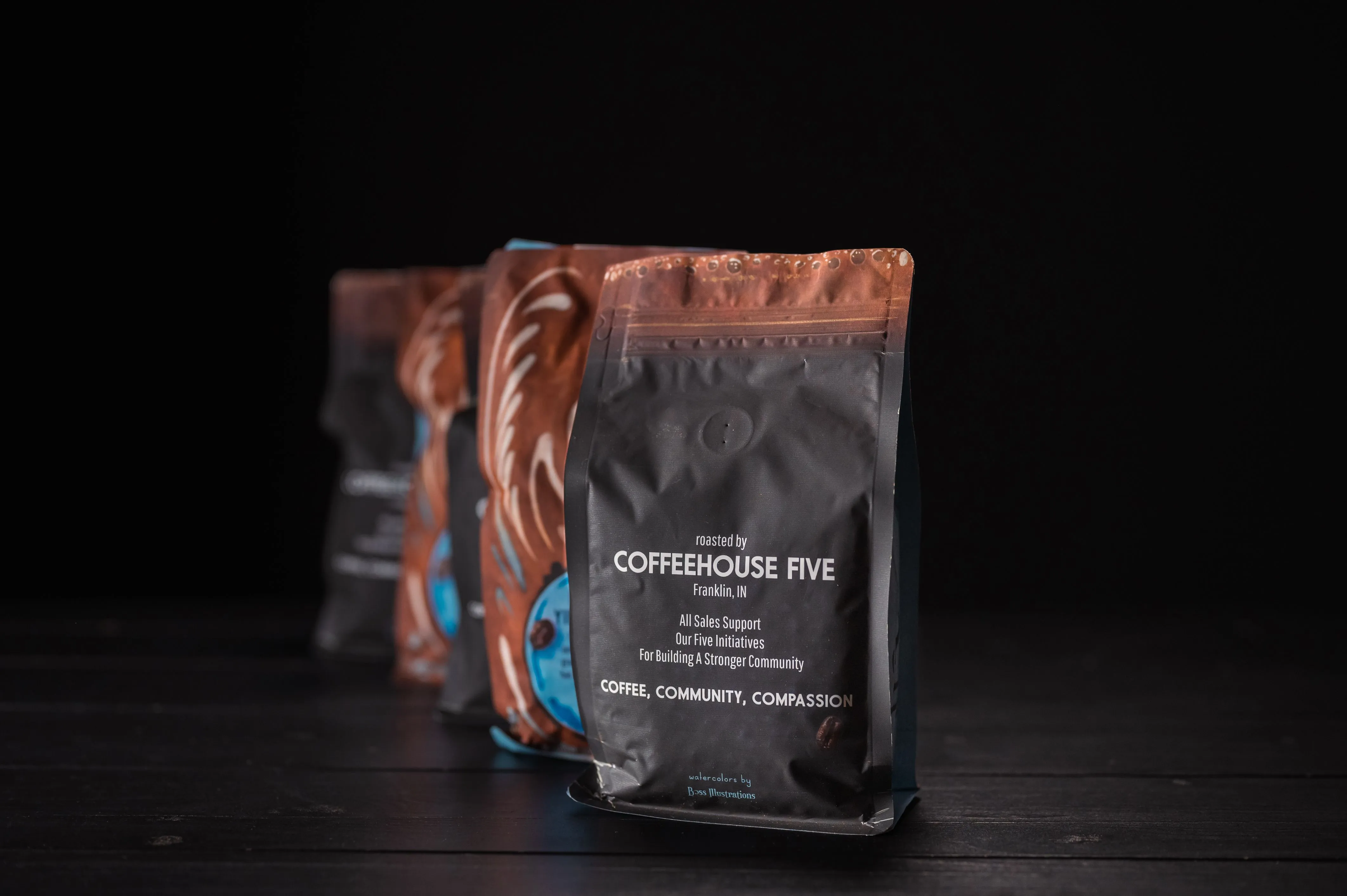 Three bags of COFFEEHOUSE FIVE branded coffee on a dark background, with the focus on the closest bag.