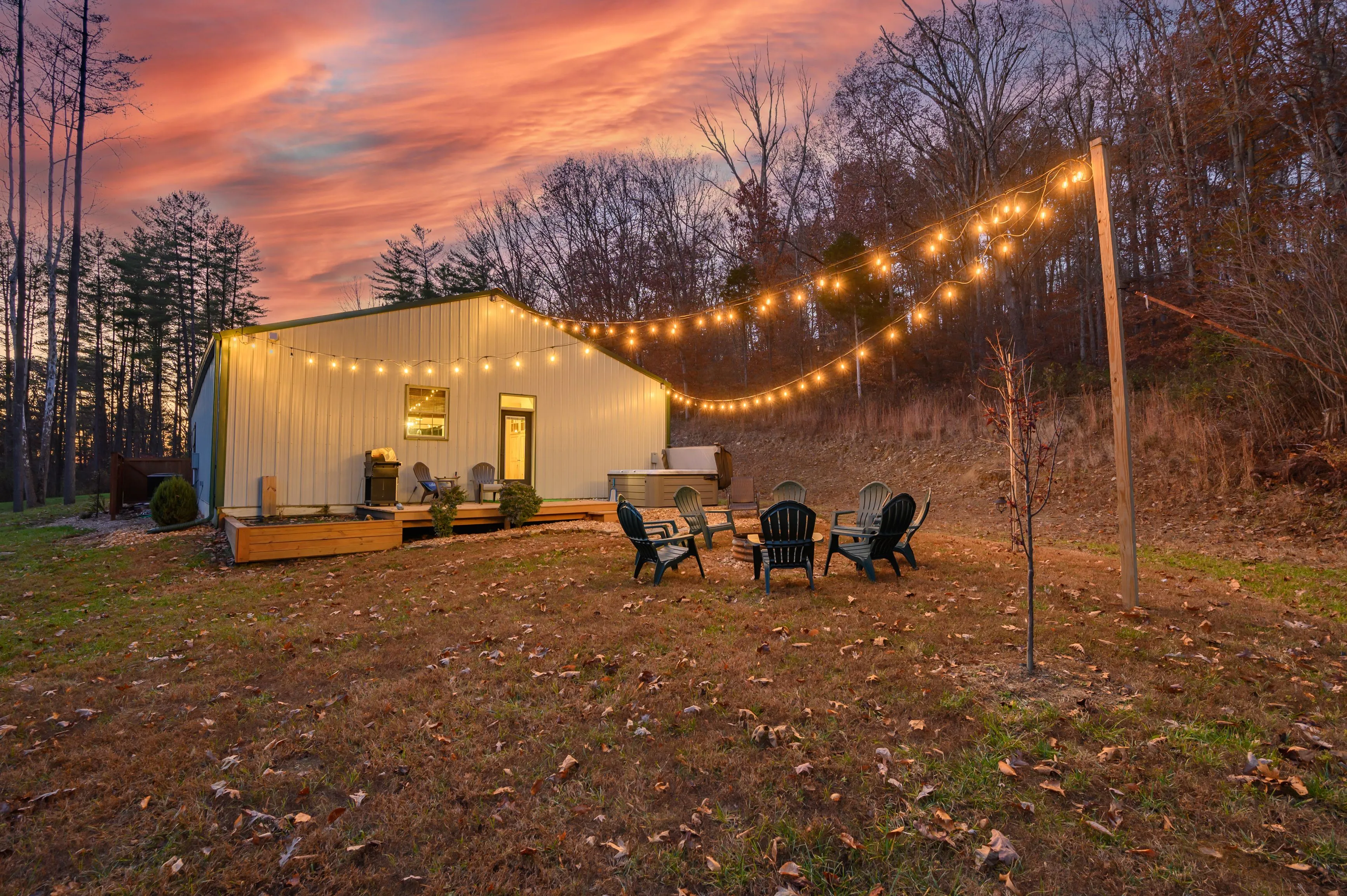 A cozy outdoor seating area with string lights at twilight in front of a modern tiny house.
