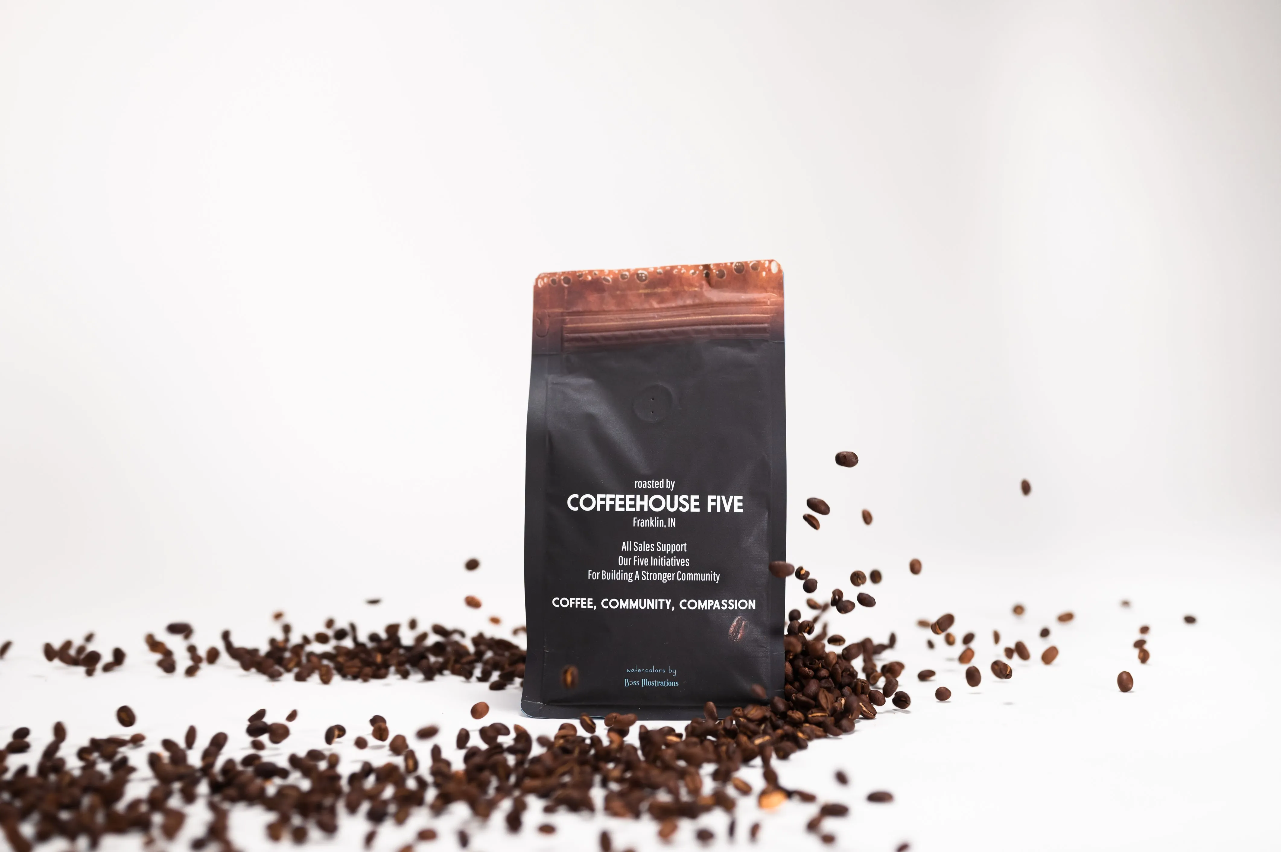 A package of Coffeehouse Five coffee surrounded by scattered coffee beans on a white background.