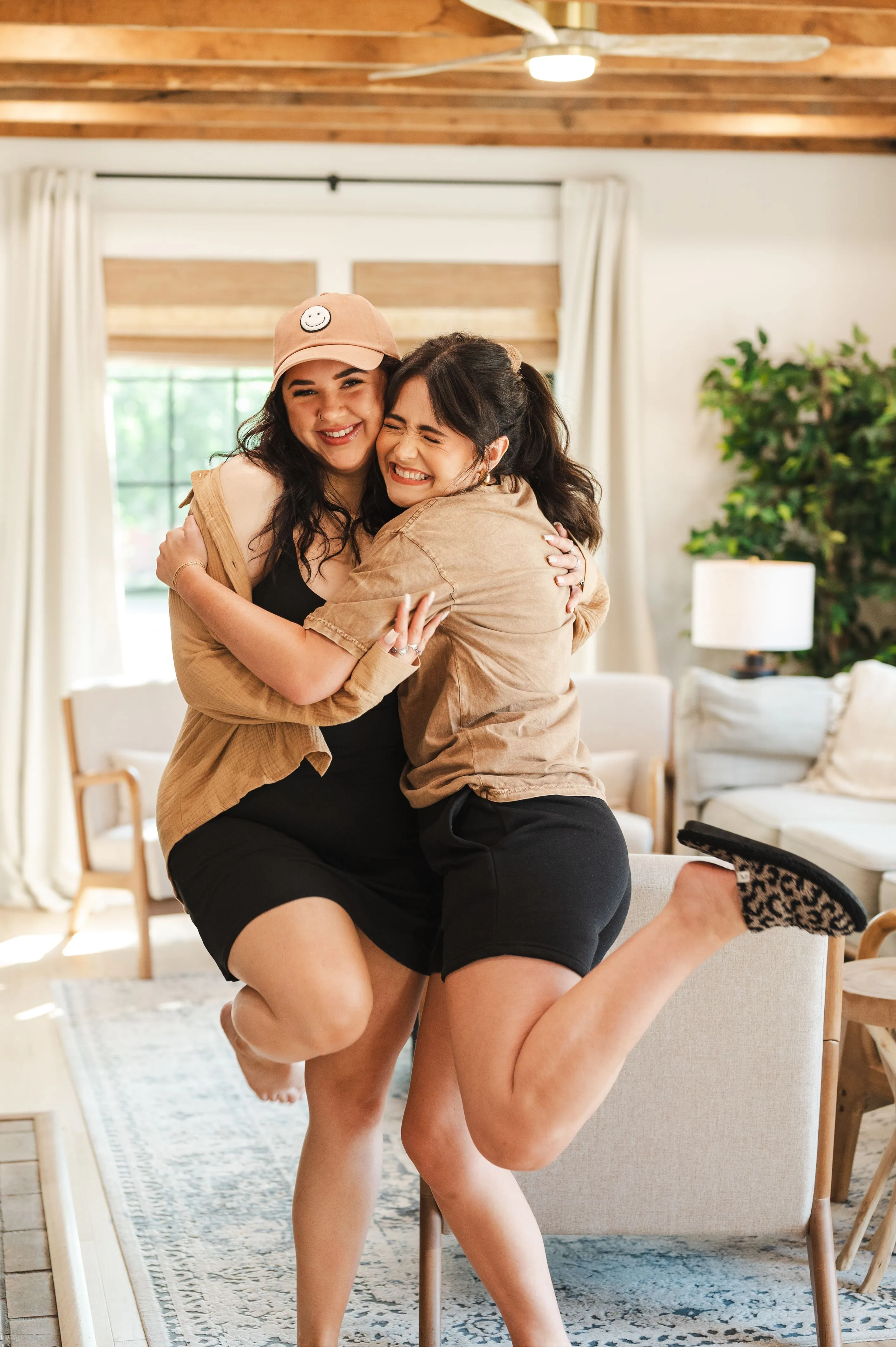 Two happy women embracing and smiling in a cozy living room setting.