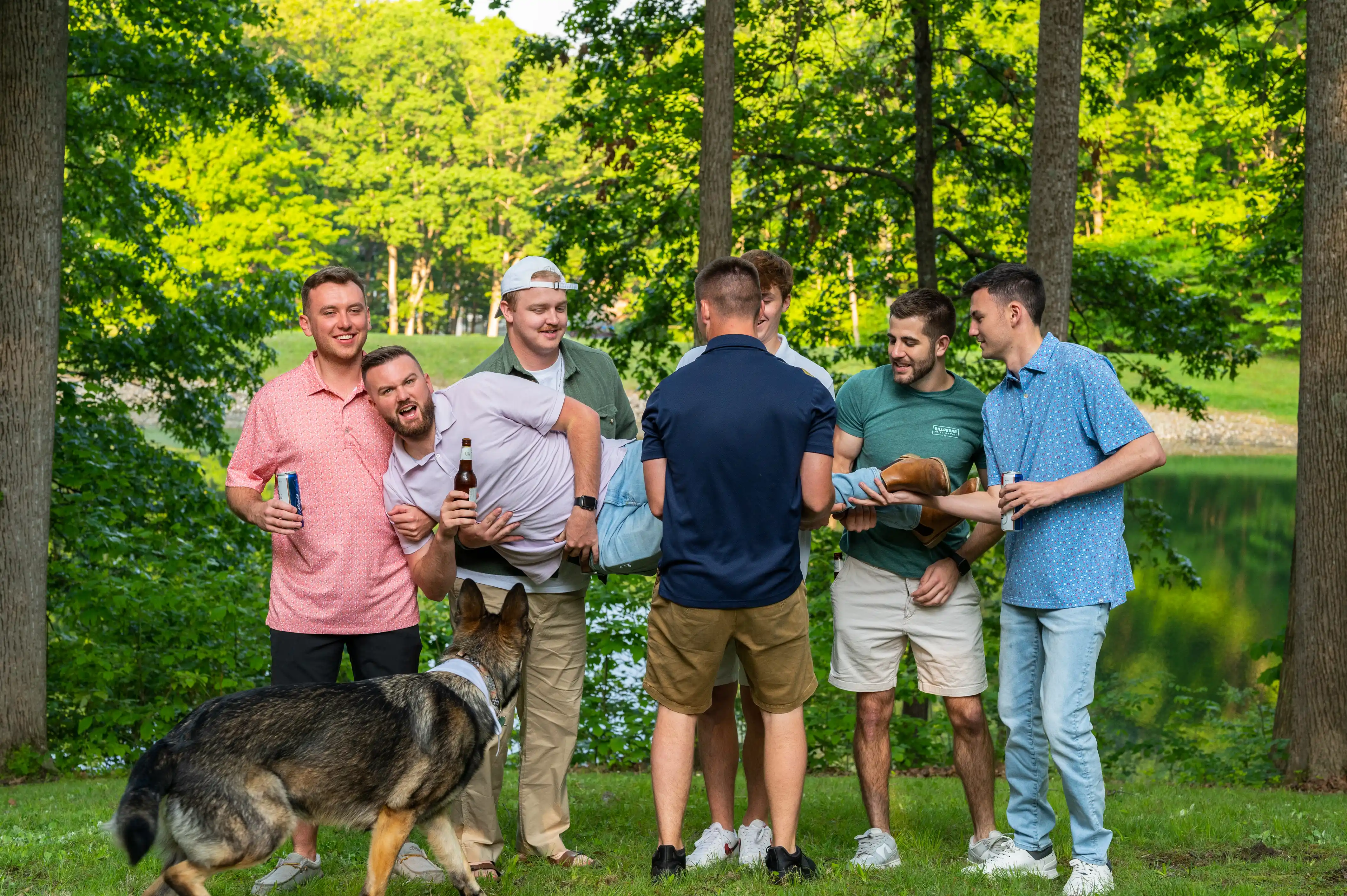 Group of friends enjoying a barbecue in a park with a dog walking by.