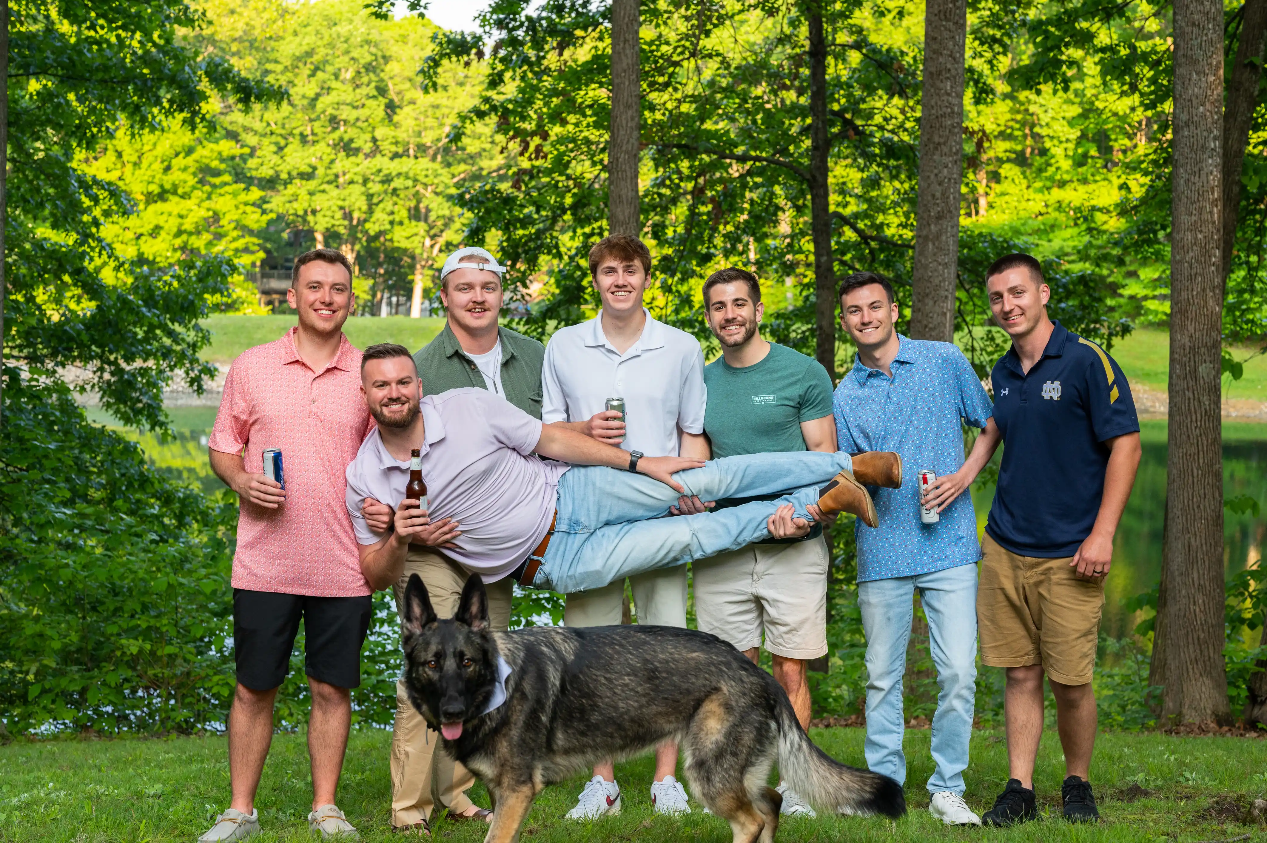 Group of smiling friends posing outdoors with a dog.