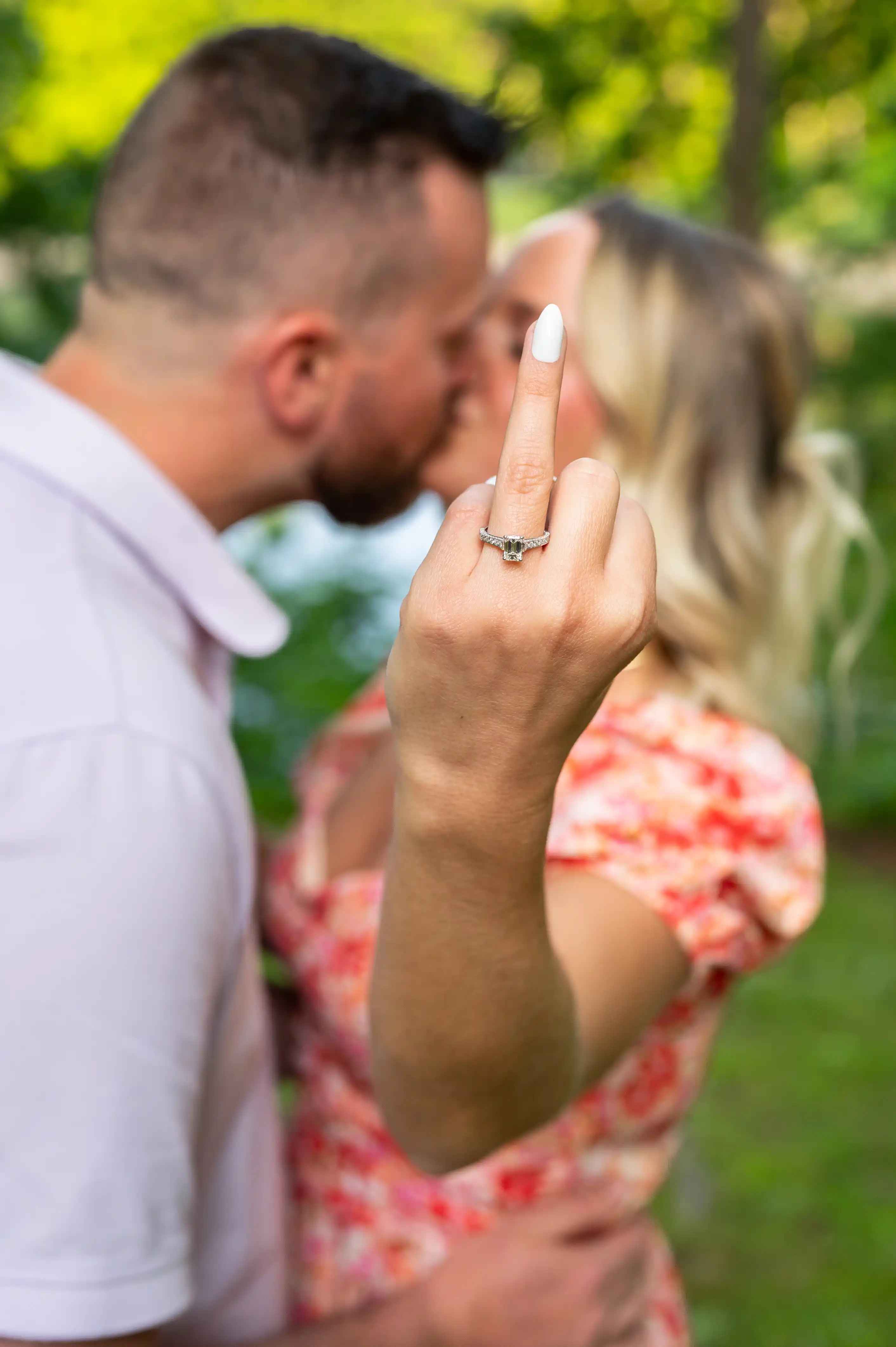 Couple sharing an intimate forehead touch with blurred greenery in the background.