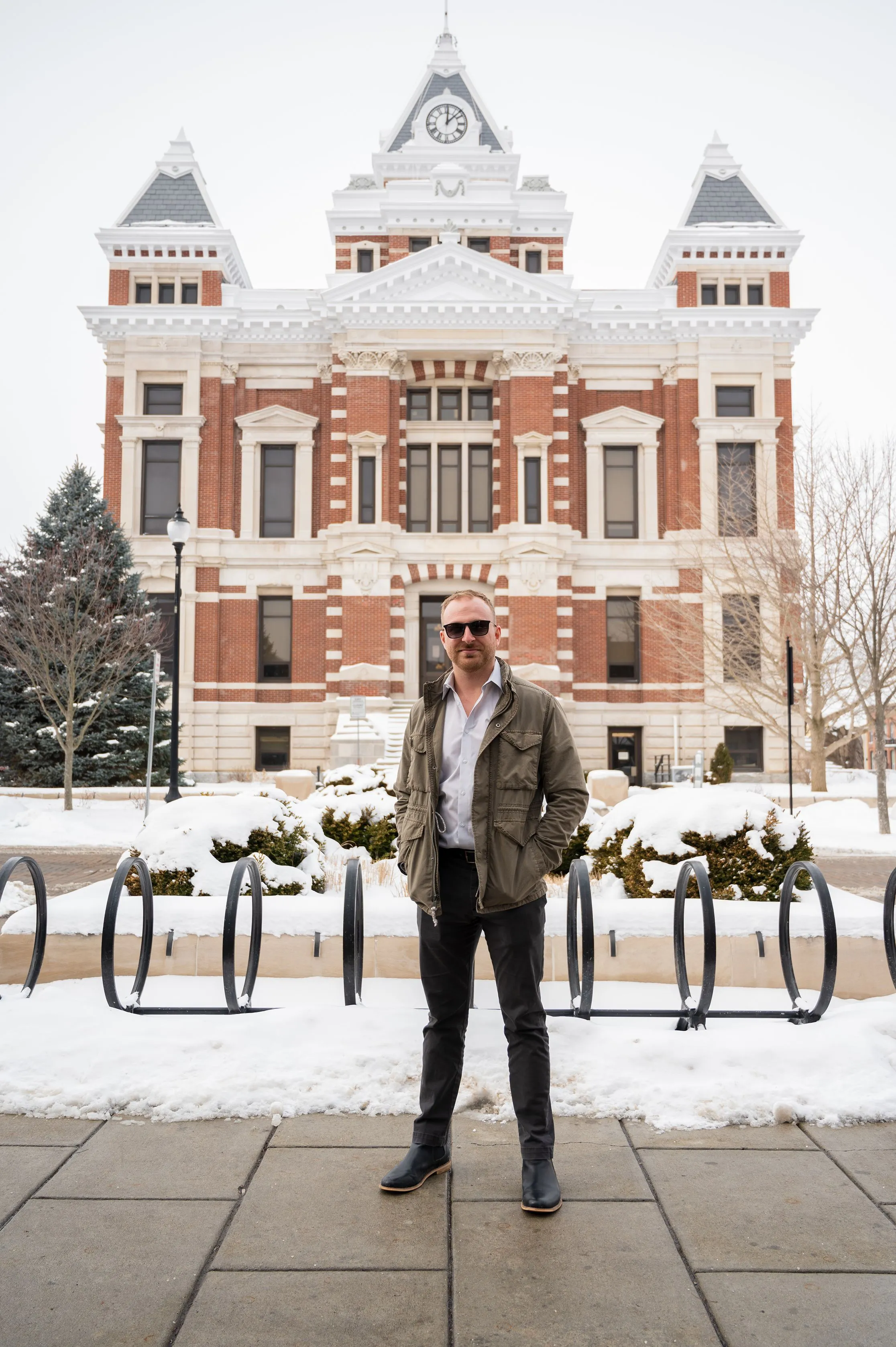 Person standing in front of a historic brick building with snowfall.