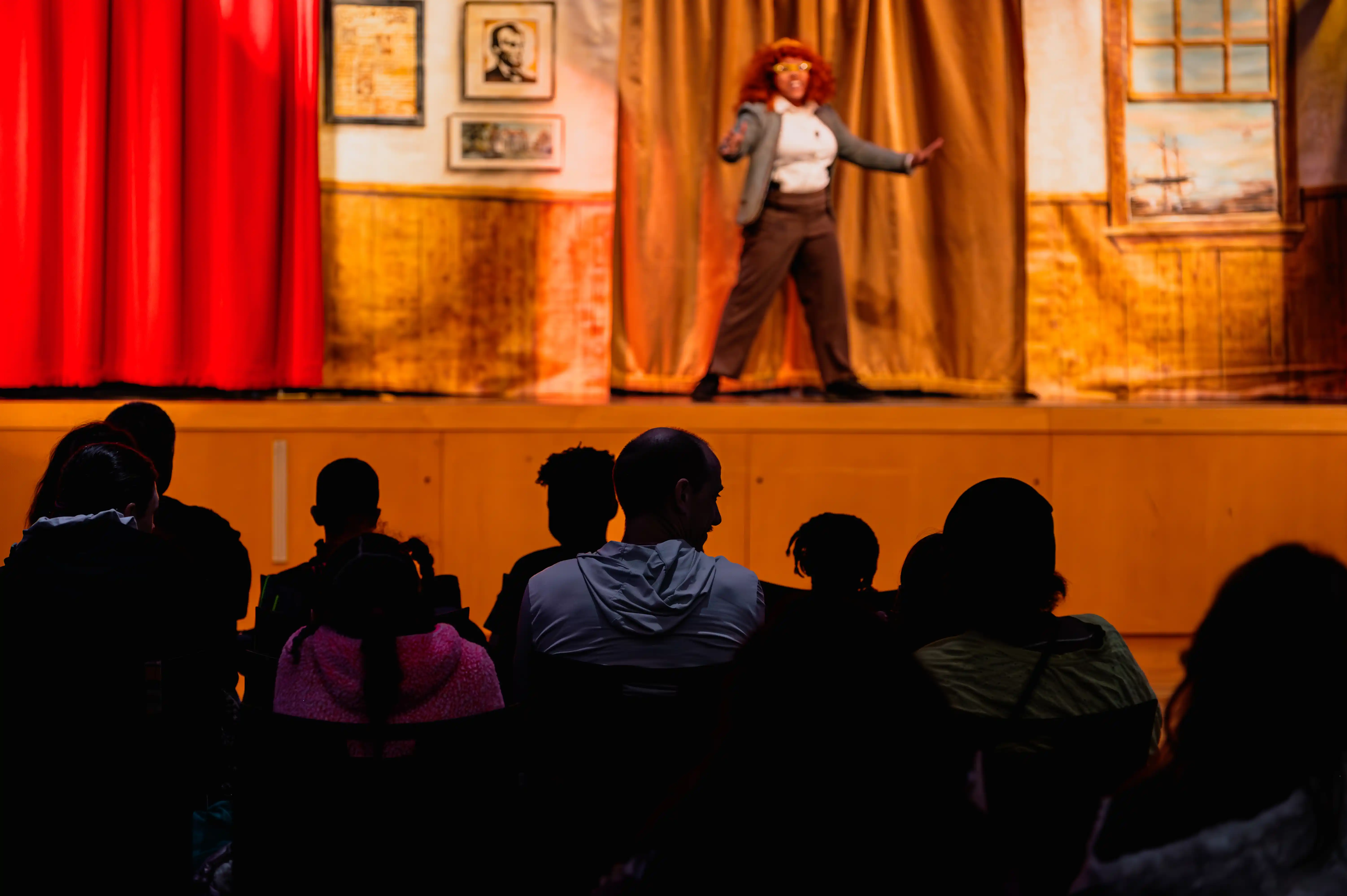 Audience watching a performer on stage at a theater production.