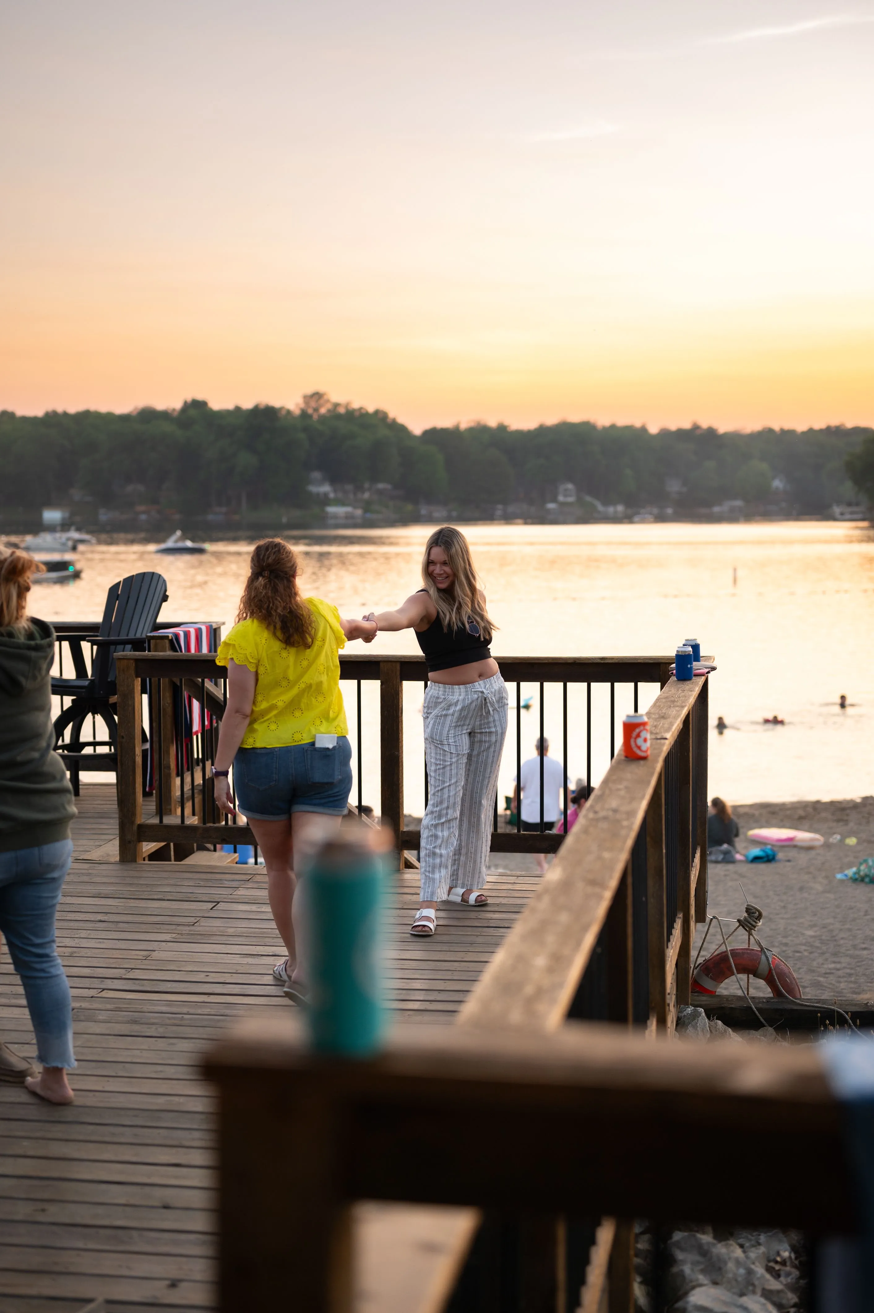 People enjoying a serene lakeside view from a deck during sunset.