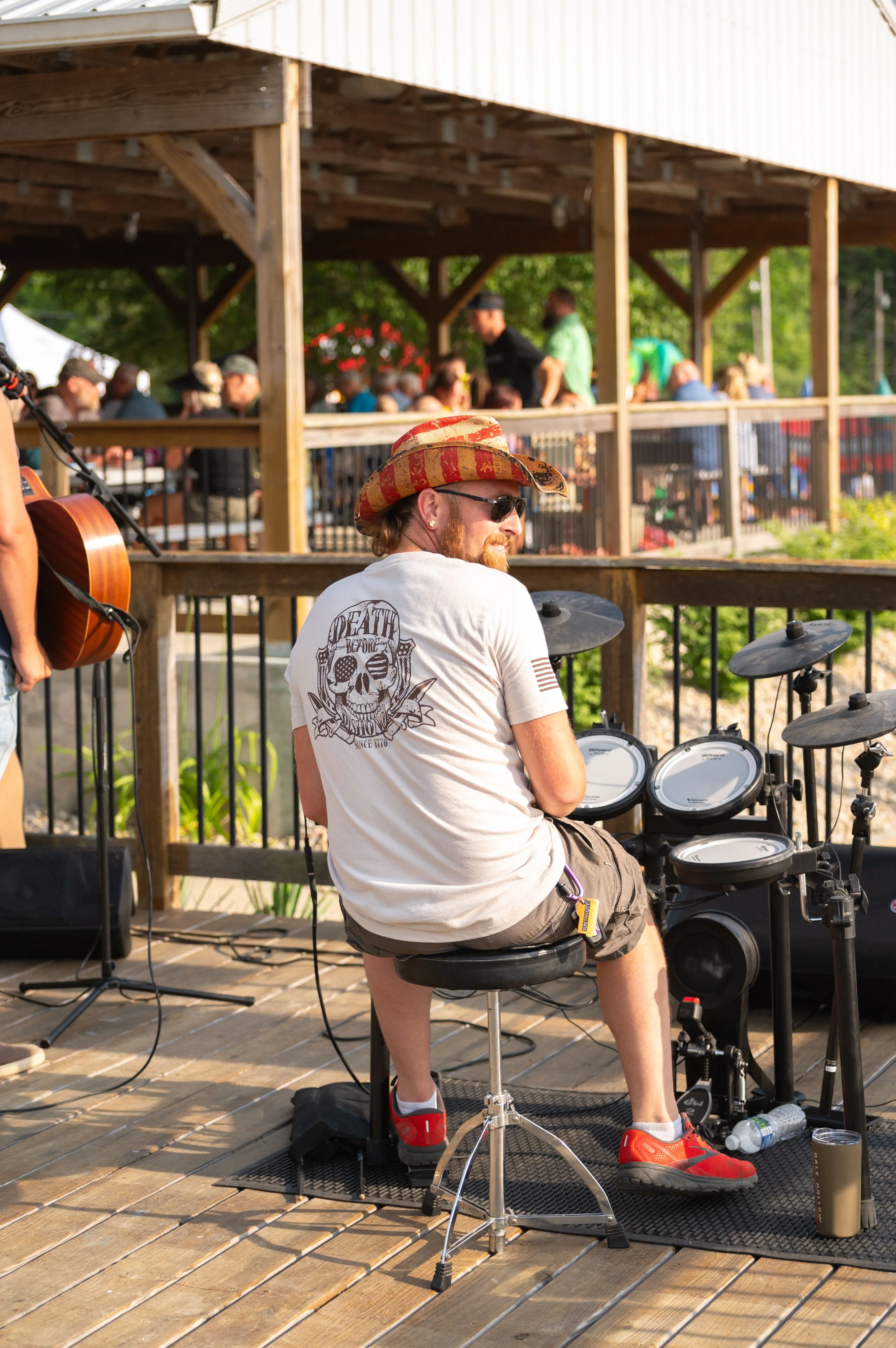 Person sitting on a stool in an outdoor setting with musical equipment nearby.