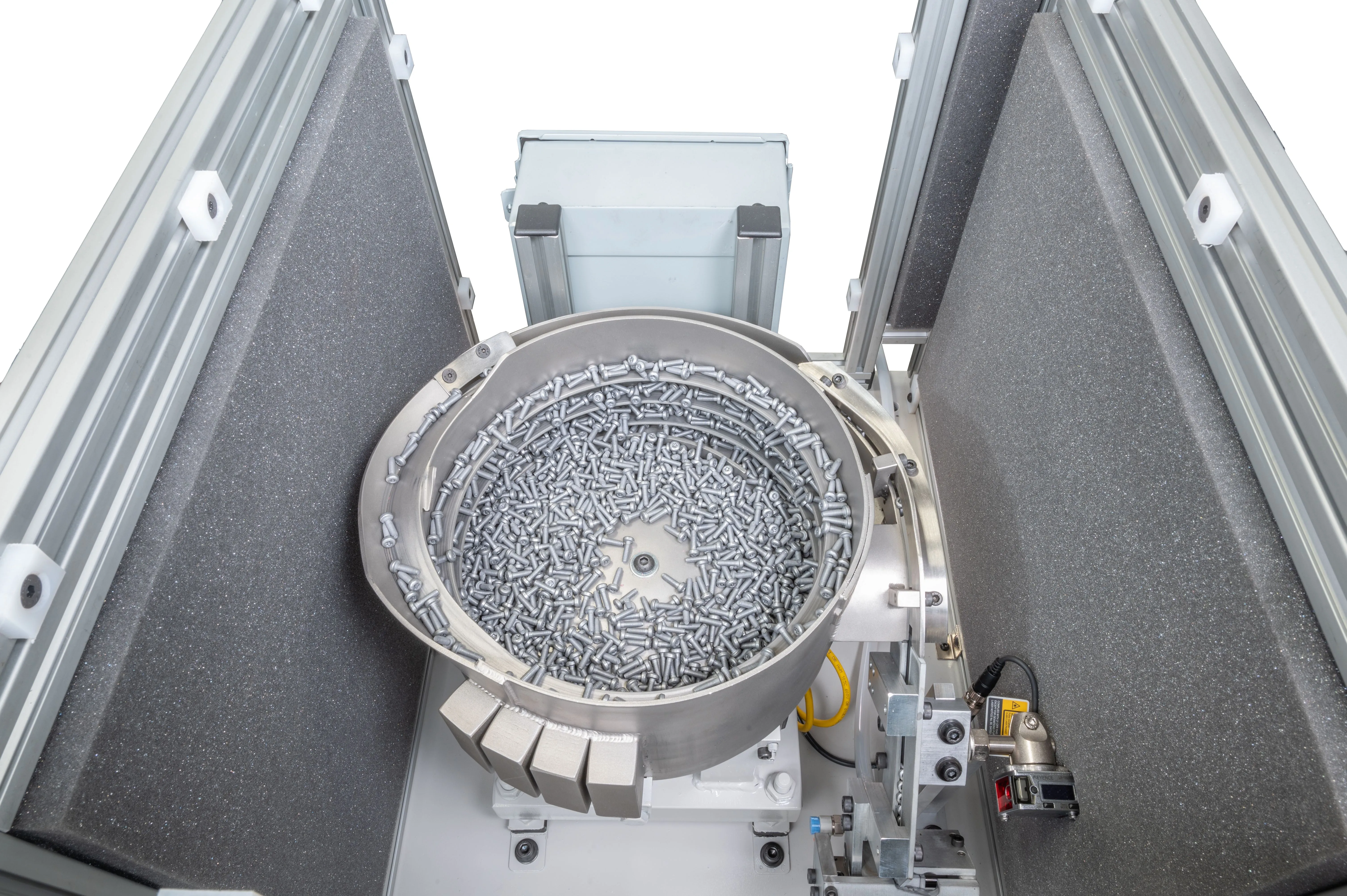 Industrial feeder equipment with a large number of metal fasteners in a vibratory bowl for automated assembly.