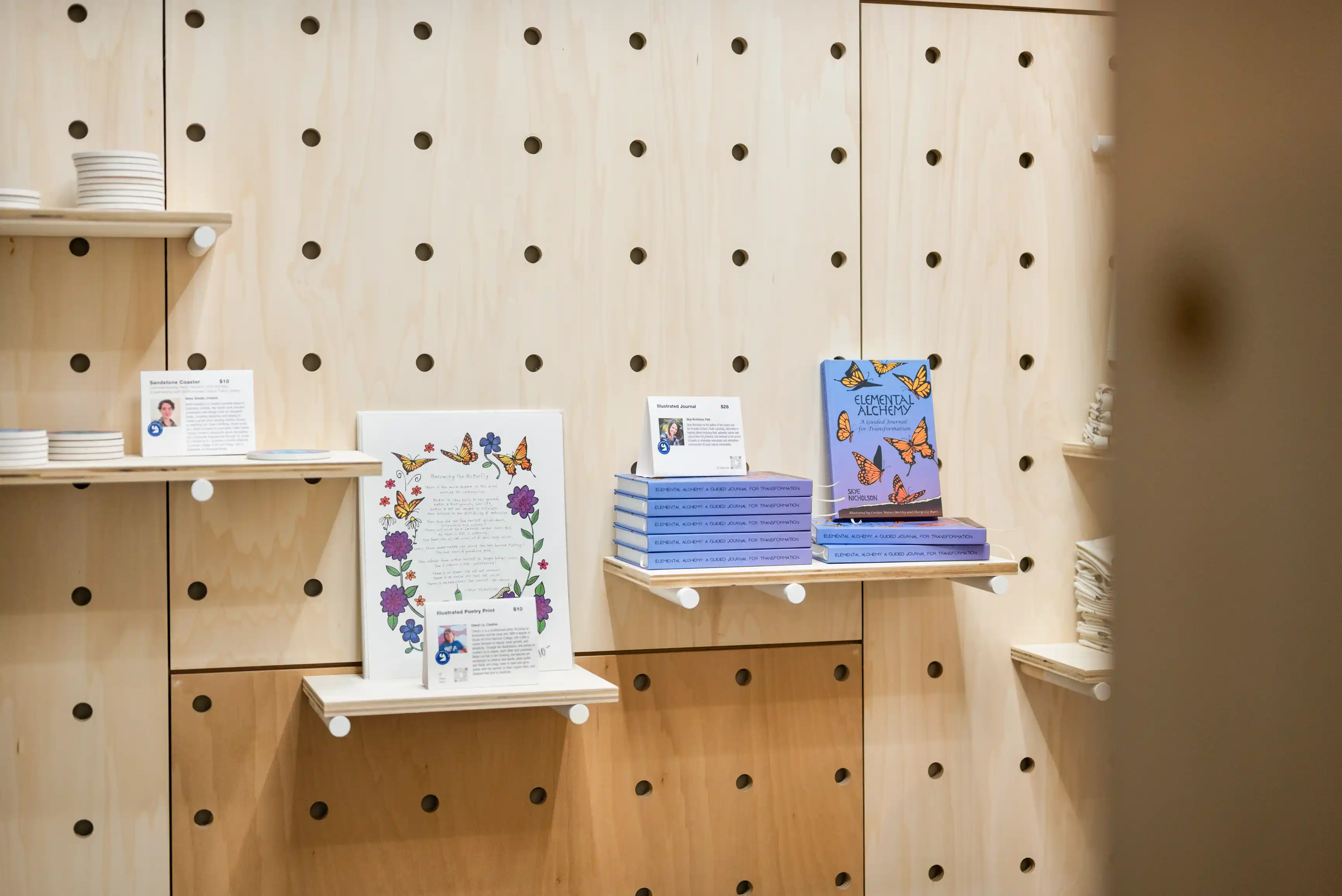 Books and informational cards displayed on wooden shelves with a pegboard wall in the background.