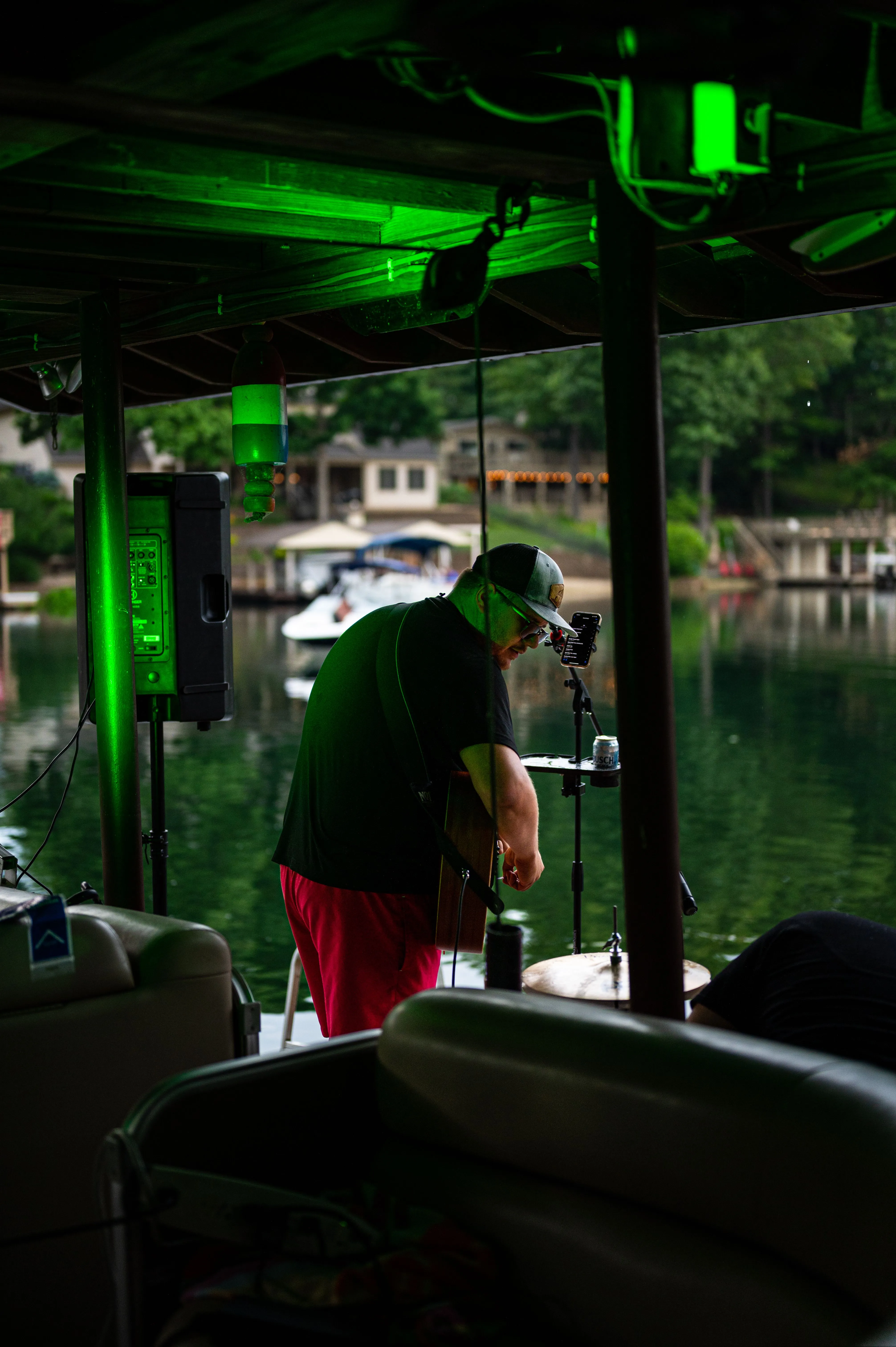 A boat captain steering from the helm inside the cabin with lake and dock visible through the windows.