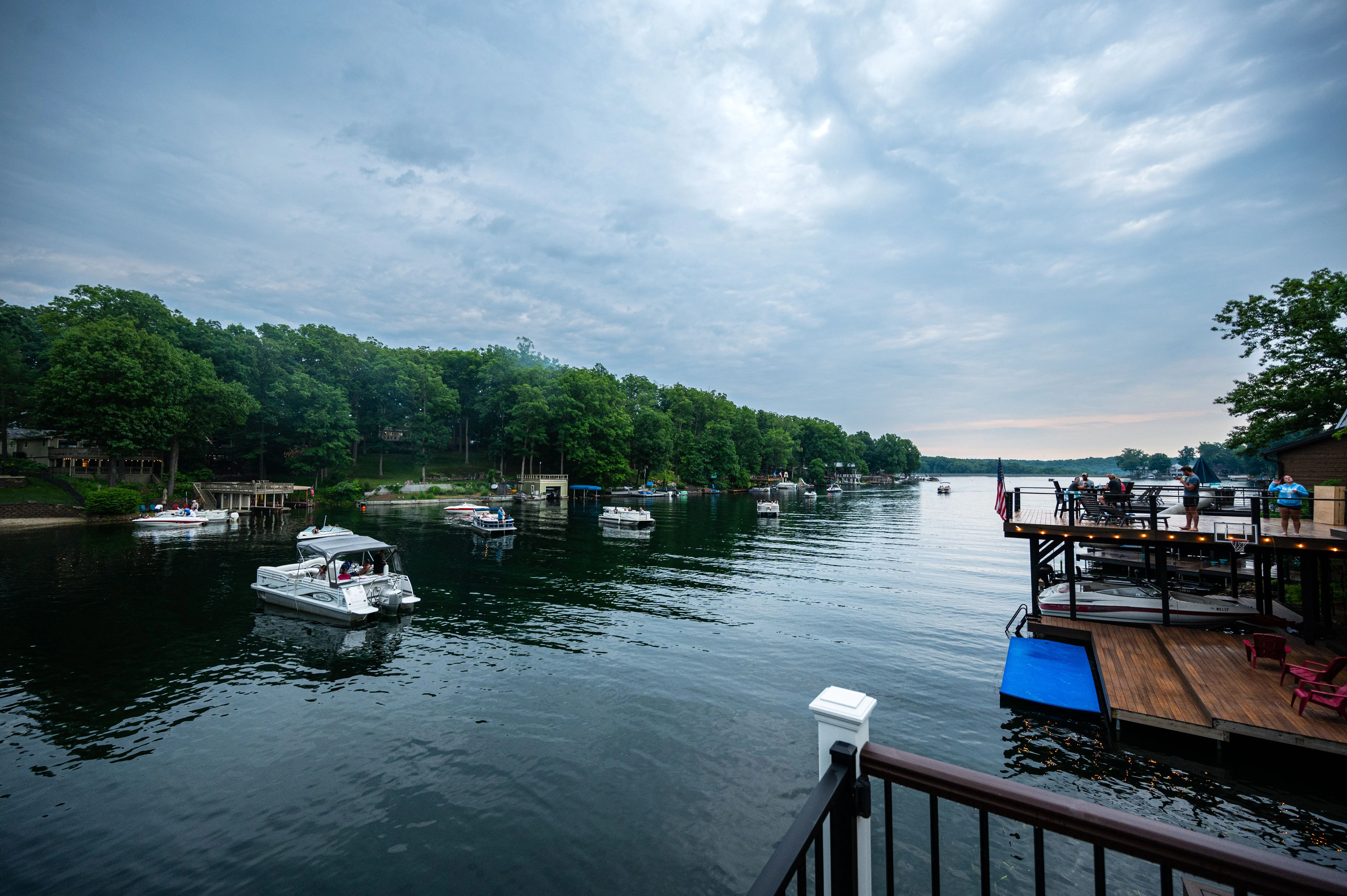 Scenic view of a calm river with boats docked along the shore, as seen from a balcony with railing.