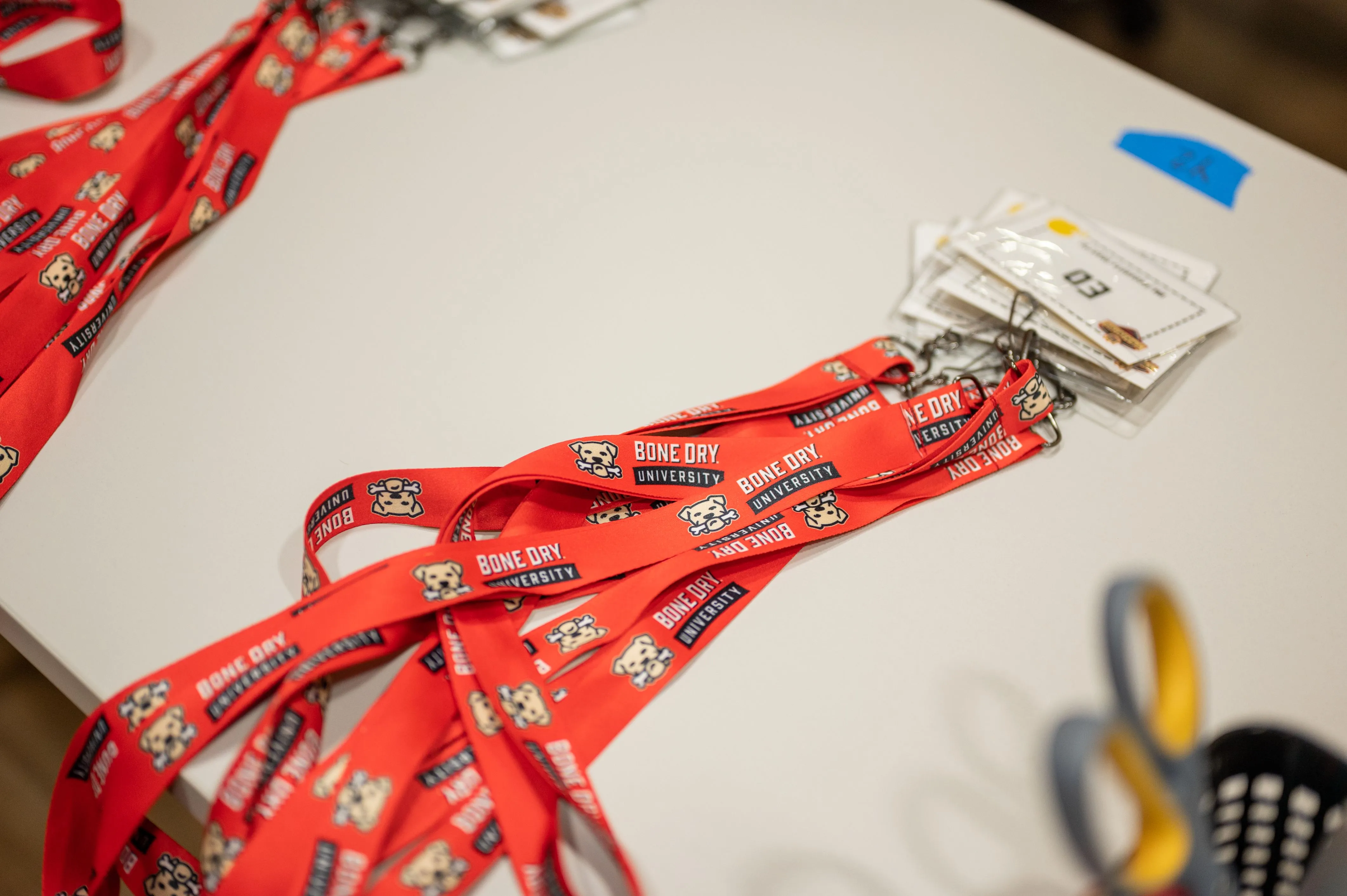 Red lanyards with event passes on a table alongside office supplies.