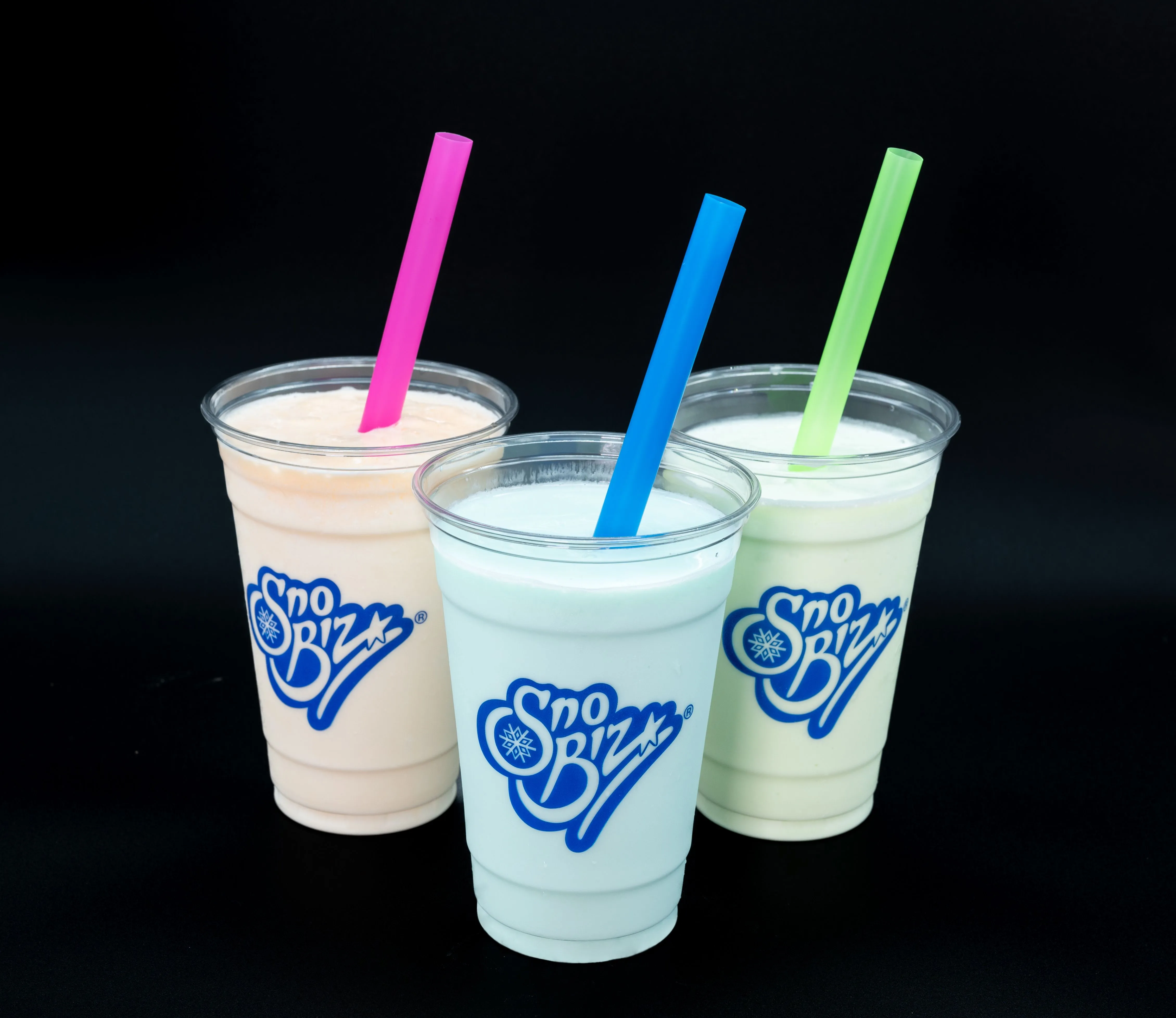 Three cups of Sno Biz shaved ice beverages with different flavors, each with a colorful straw, on a black background.