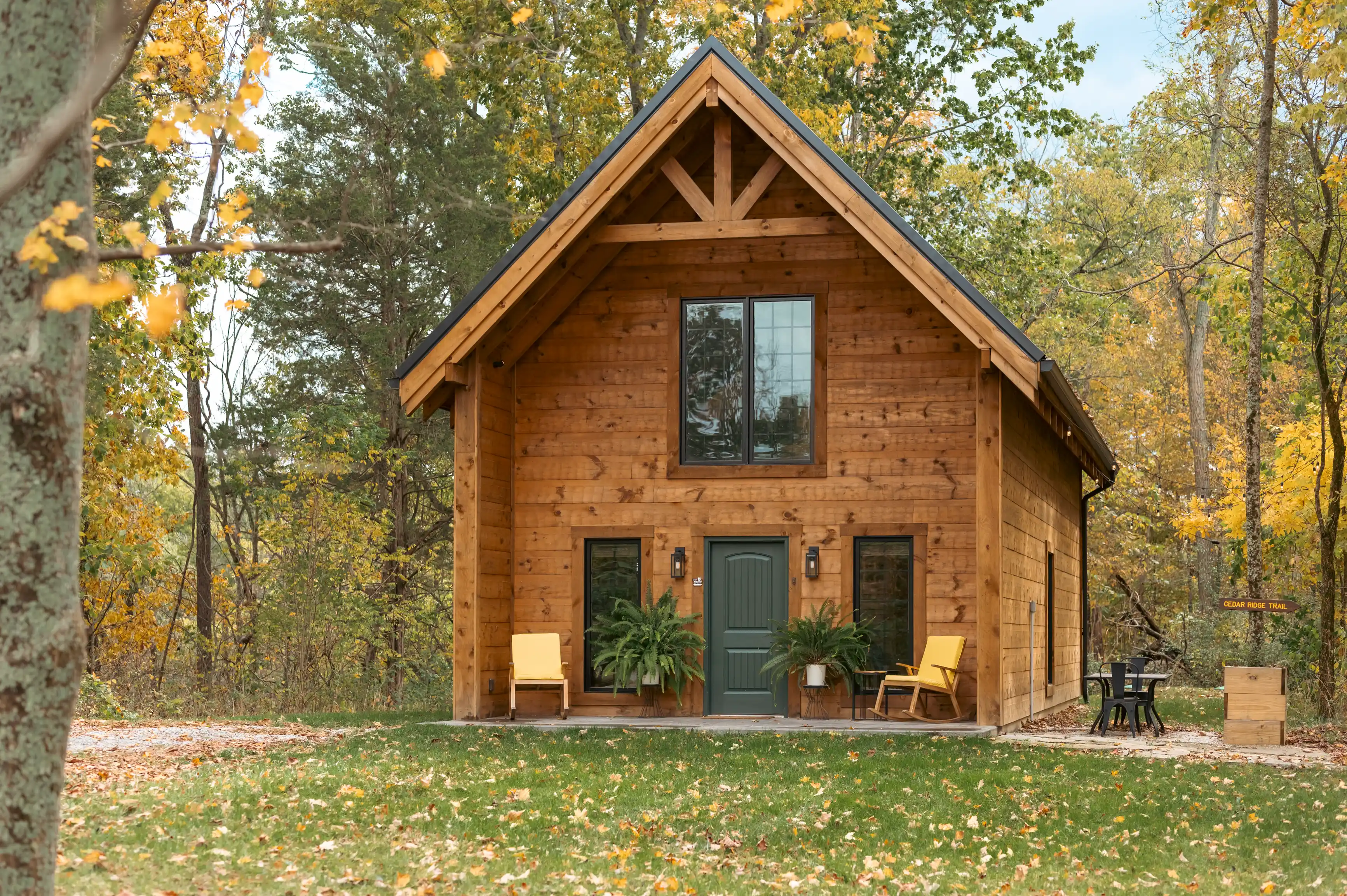 Wooden cabin with large windows surrounded by autumn foliage.