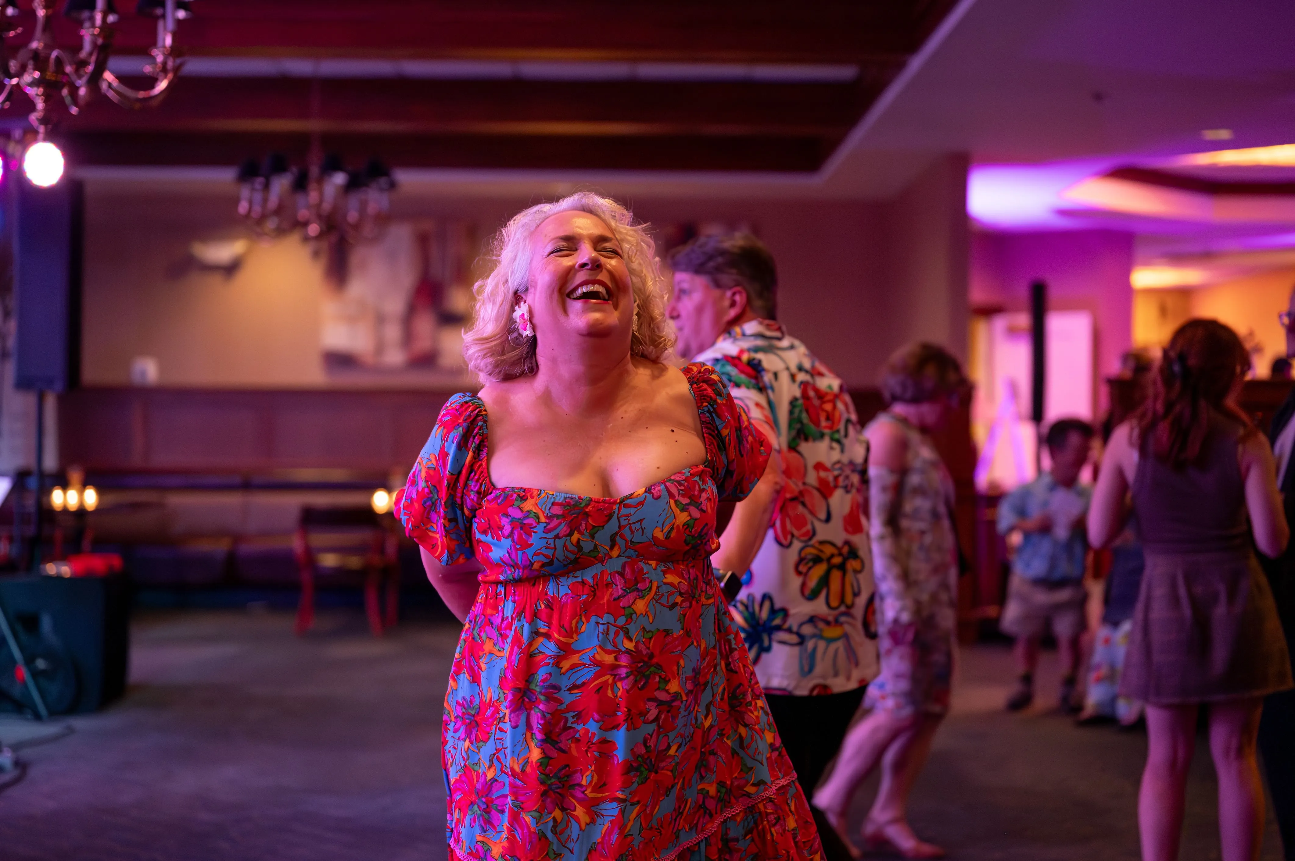 Joyful woman dancing at a party with other guests in the background.