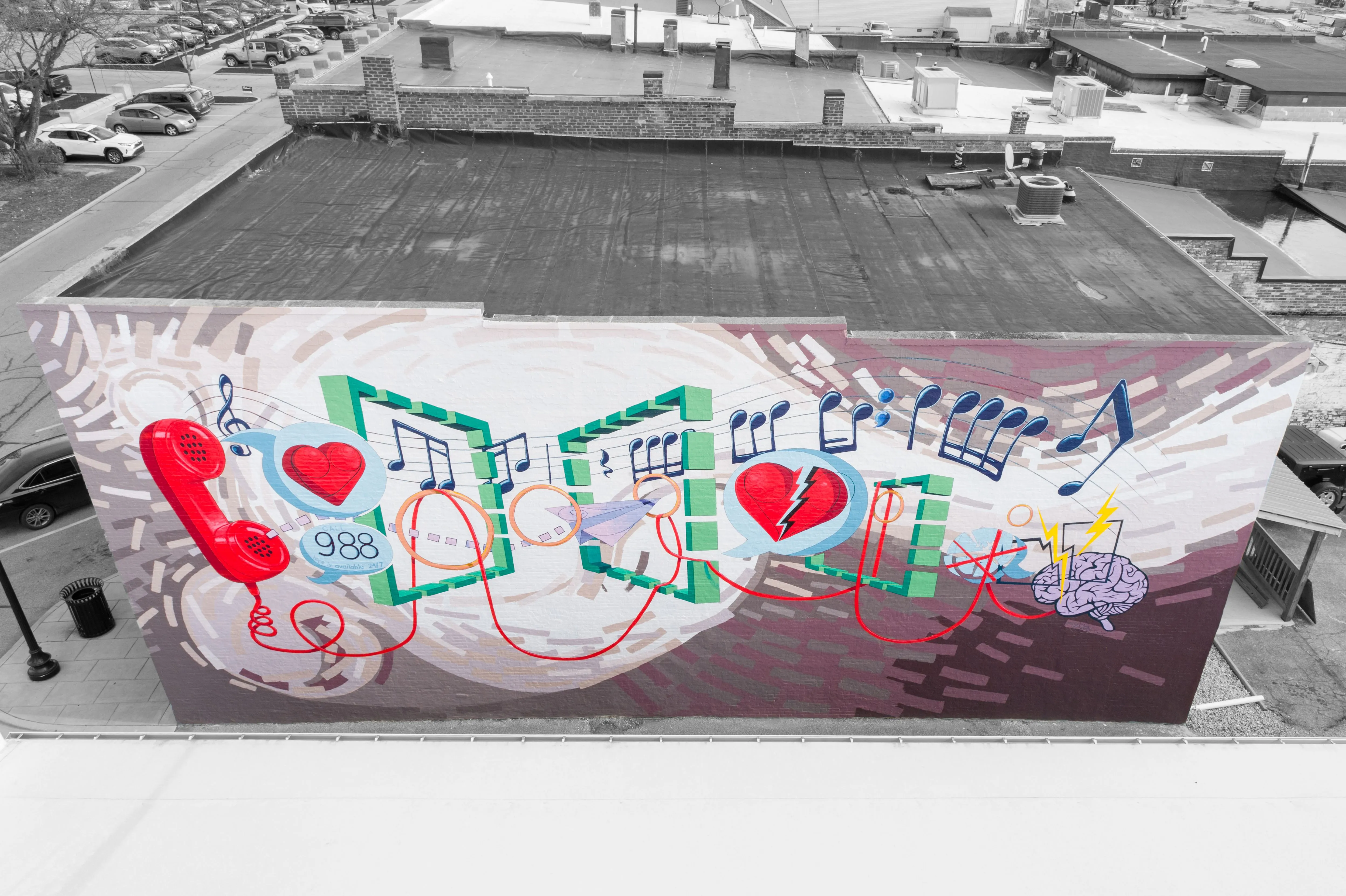 Colorful mural on a building's facade in an urban environment, with musical and heart symbols, in a black and white cityscape.