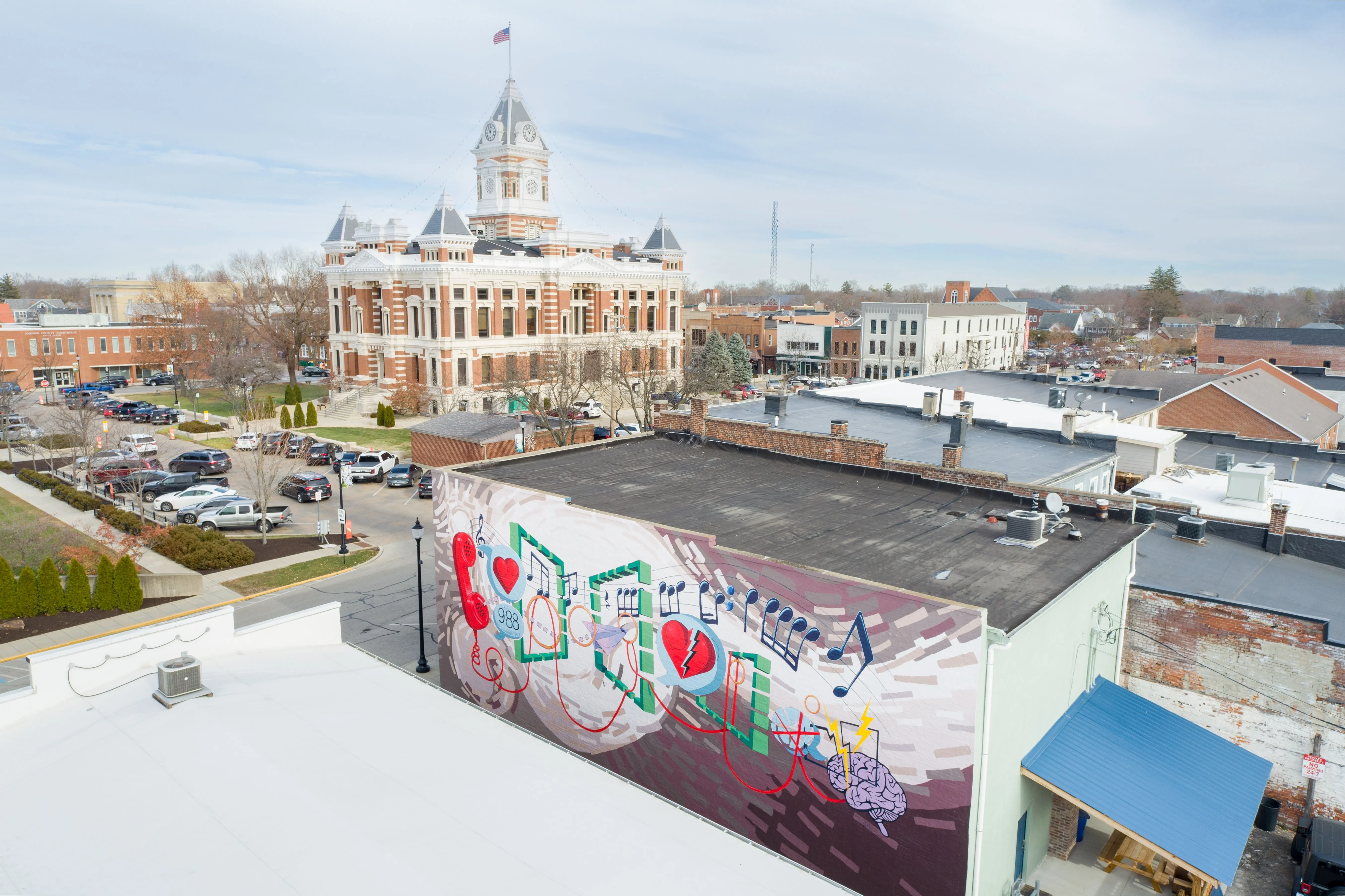 Aerial view of a cityscape with graffiti art on a building foreground and a historic domed building in the background.