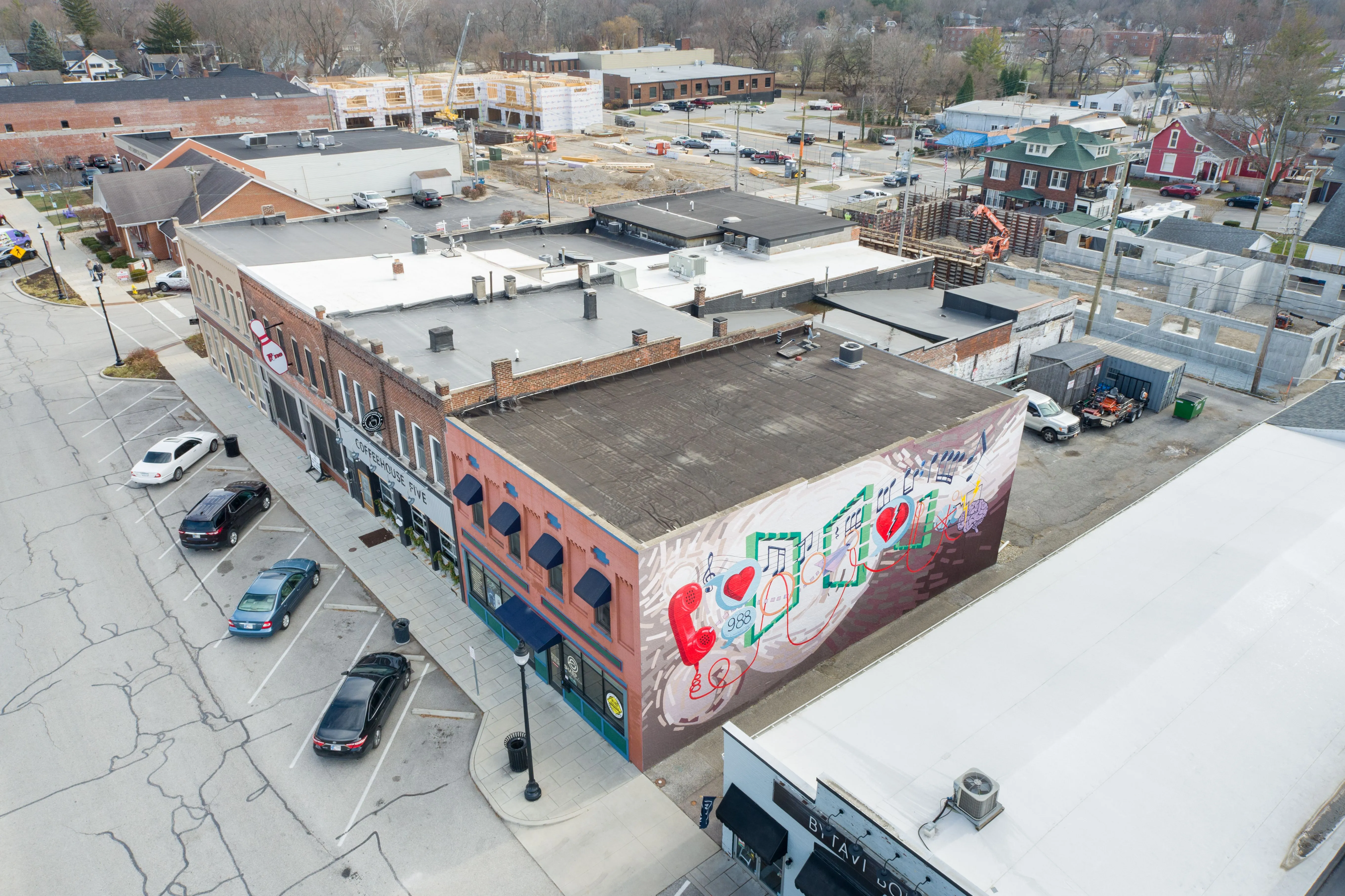 Aerial view of a city block with a building featuring graffiti art, surrounded by cars and adjacent buildings.