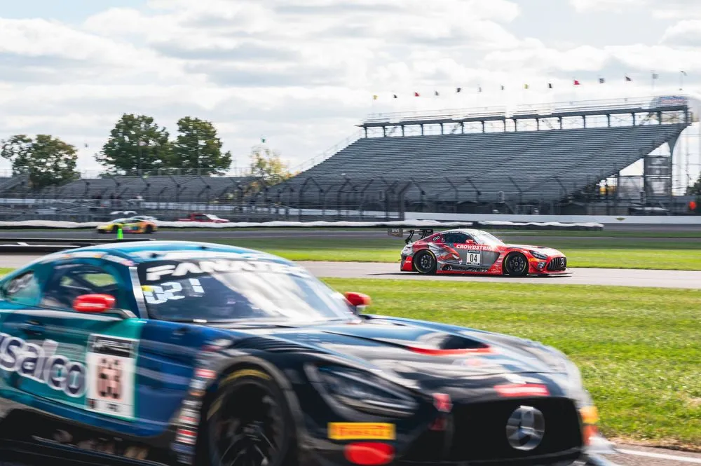 Race cars on a track with a focus on a red Mercedes-AMG GT3 in the foreground, with blurred motion conveying speed.