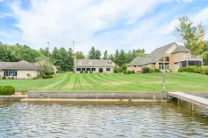 Suburban homes with well-manicured lawns by a calm lake with a small dock.