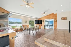 Spacious lake house interior with an open-plan kitchen and dining area, featuring large windows with lake view, tile flooring, and a walkout to the patio.