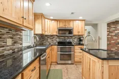 Spacious kitchen interior with wooden cabinets, stainless steel appliances, and granite countertops.