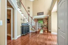 Elegant house interior with hardwood floors, staircase leading to upper level, and open doors to connecting rooms.
