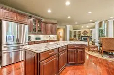 Spacious kitchen interior with rich wooden cabinets, granite countertops, and glossy hardwood flooring.