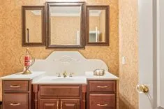 Elegant bathroom interior with a wooden vanity cabinet, double sinks, framed mirror, and decorative wallpaper.