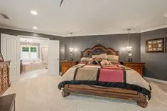 Elegant master bedroom with large bed, decorative headboard, and ensuite bathroom entrance.