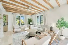 Bright, airy living room with exposed wooden beams, modern furniture, and large windows with garden view.