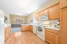 Bright, spacious kitchen with wooden cabinets, white appliances, and hardwood floor.